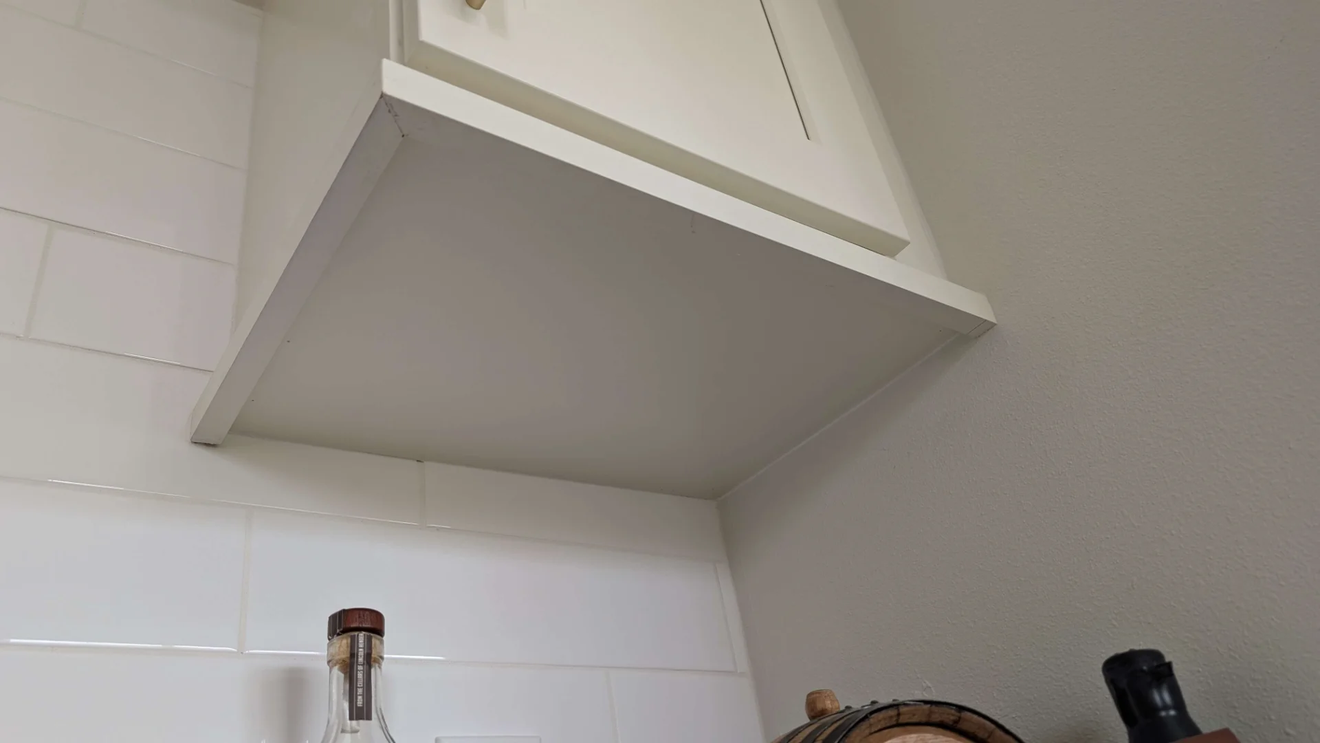 Transitional kitchen design in a Driftwood, Texas home featuring custom off-white cabinetry with gold hardware, a curved range hood, and white marble-look quartz countertops, serving homeowners in Austin and the Texas Hill Country. - Detail 7