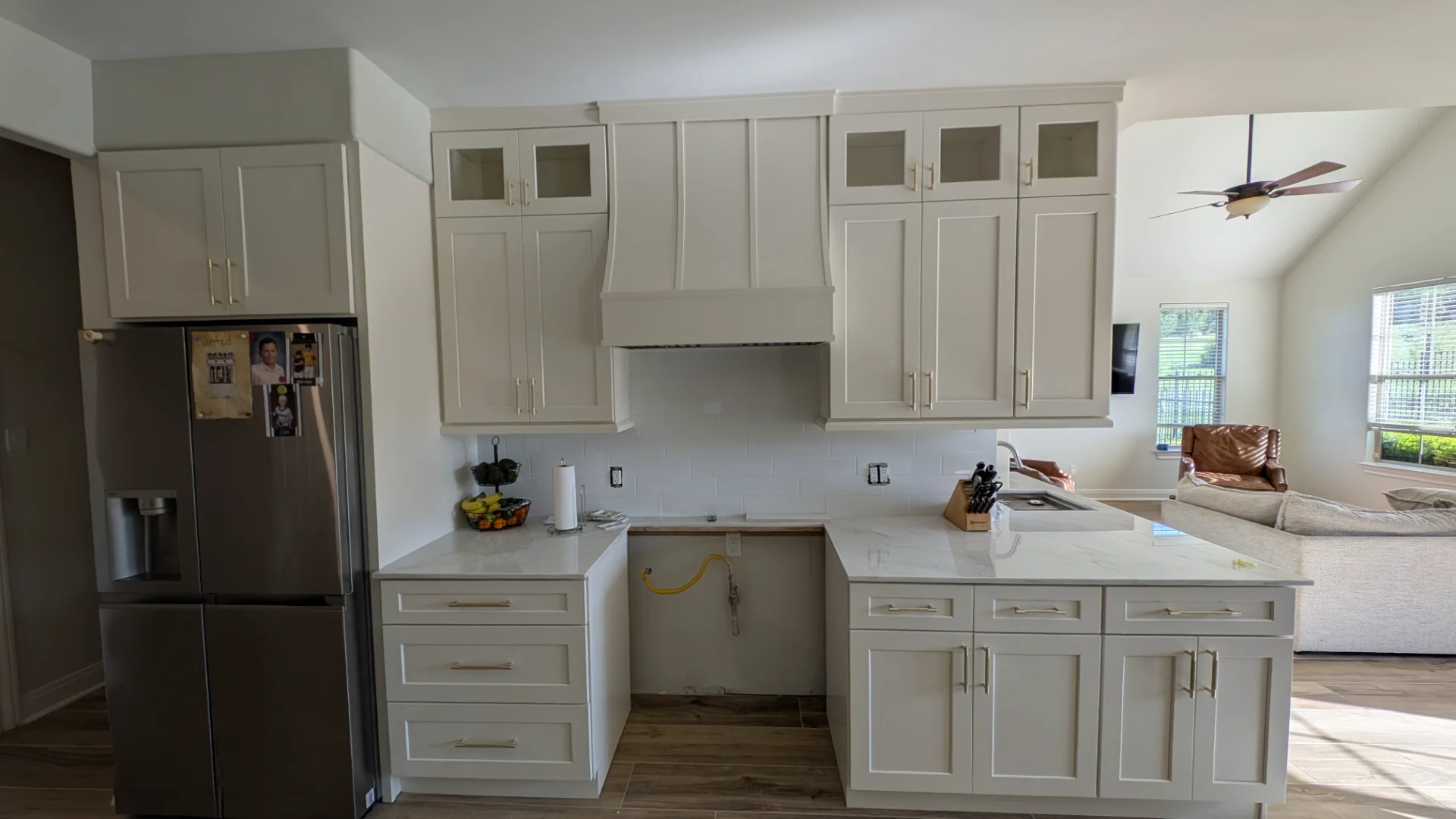 Transitional kitchen design in a Driftwood, Texas home featuring custom off-white cabinetry with gold hardware, a curved range hood, and white marble-look quartz countertops, serving homeowners in Austin and the Texas Hill Country. - Detail 5