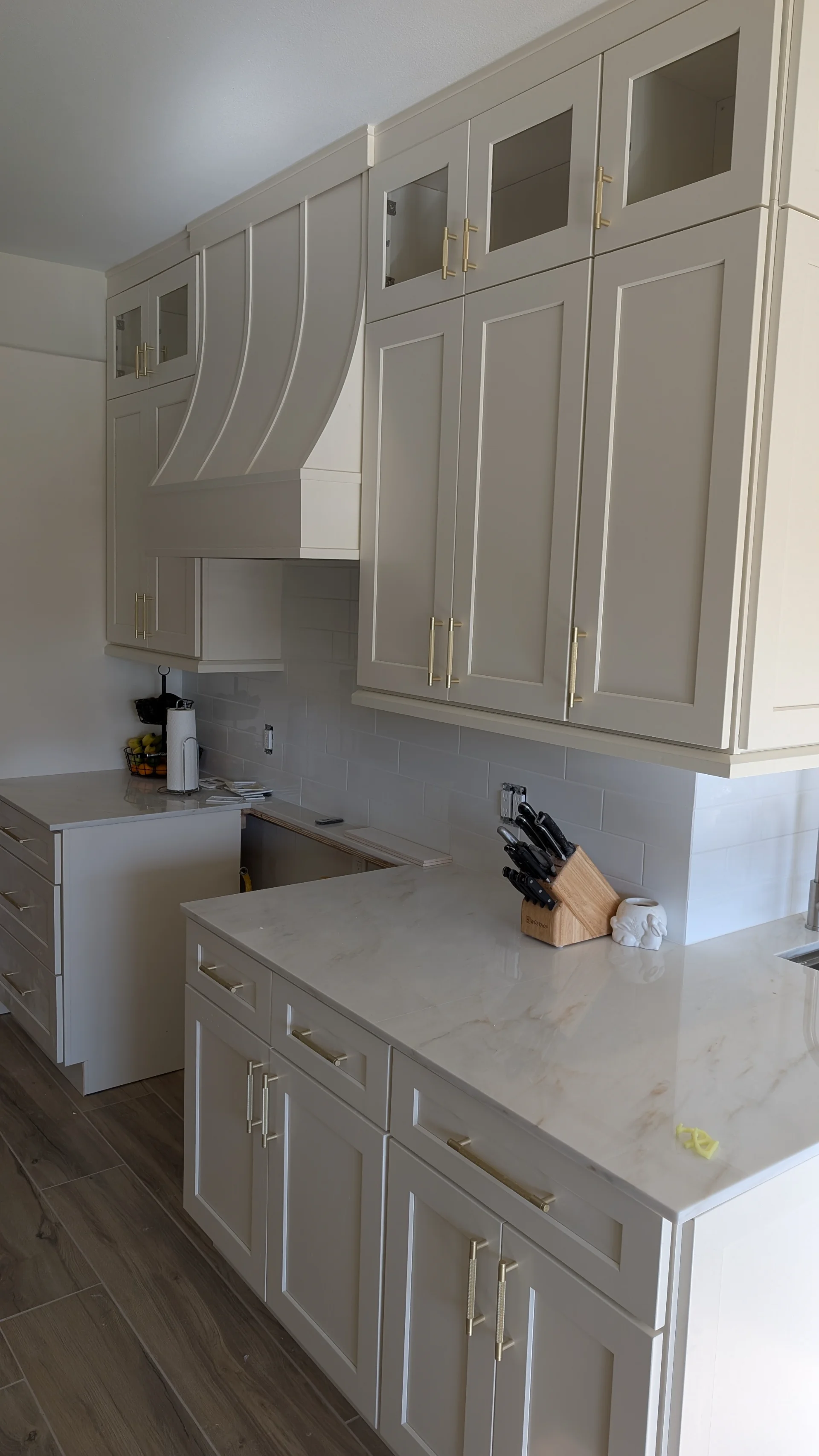 Transitional kitchen design in a Driftwood, Texas home featuring custom off-white cabinetry with gold hardware, a curved range hood, and white marble-look quartz countertops, serving homeowners in Austin and the Texas Hill Country. - Detail 3