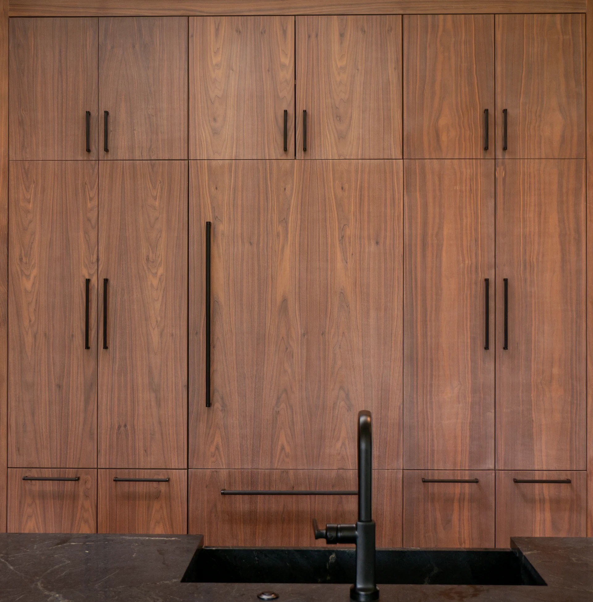 Modern grain-matched walnut kitchen in Austin, West Lake Hills, featuring a green soapstone backsplash, stainless steel range, and minimalist island cabinetry. - Detail 10