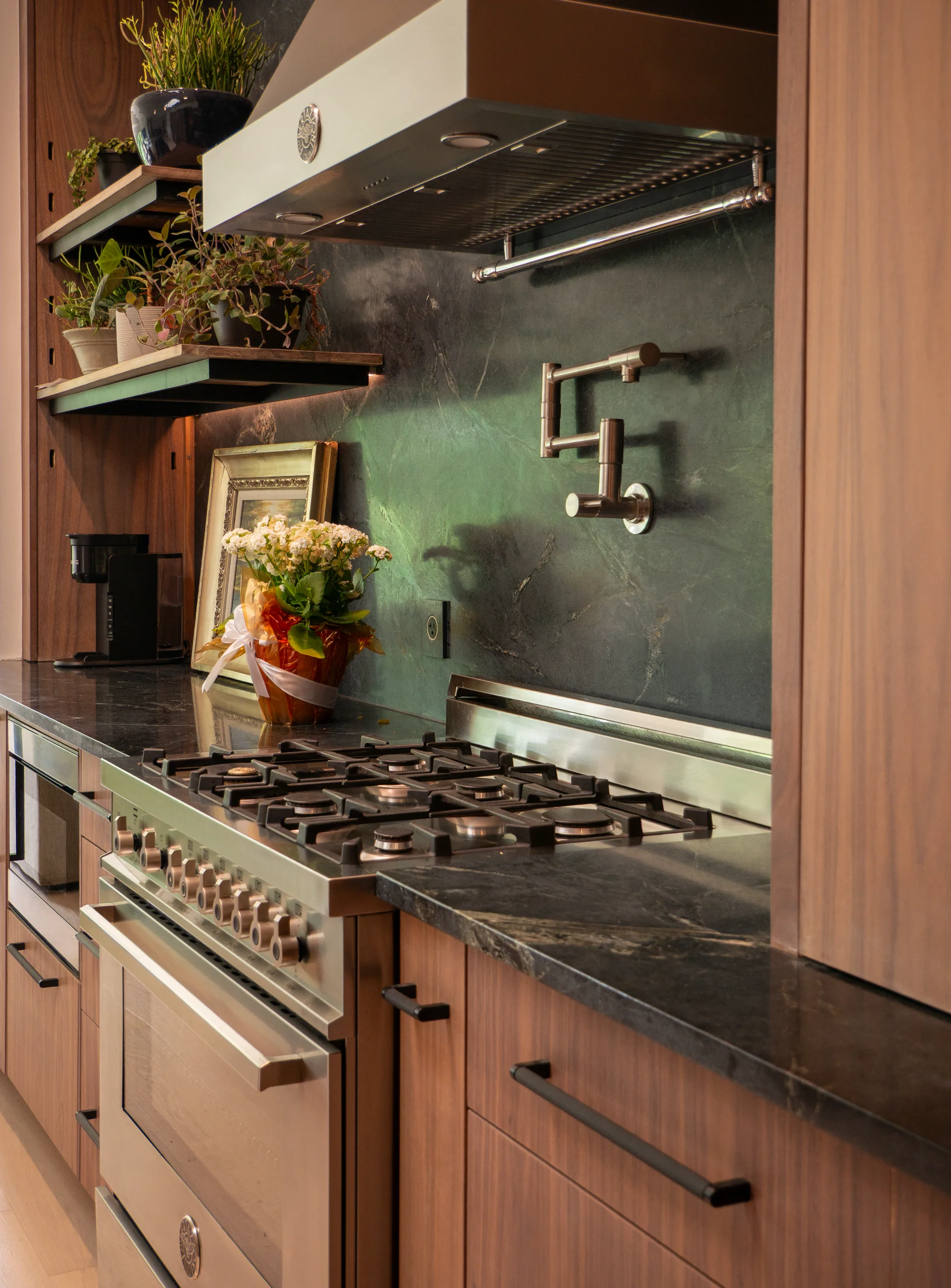 Modern grain-matched walnut kitchen in Austin, West Lake Hills, featuring a green soapstone backsplash, stainless steel range, and minimalist island cabinetry. - Detail 3