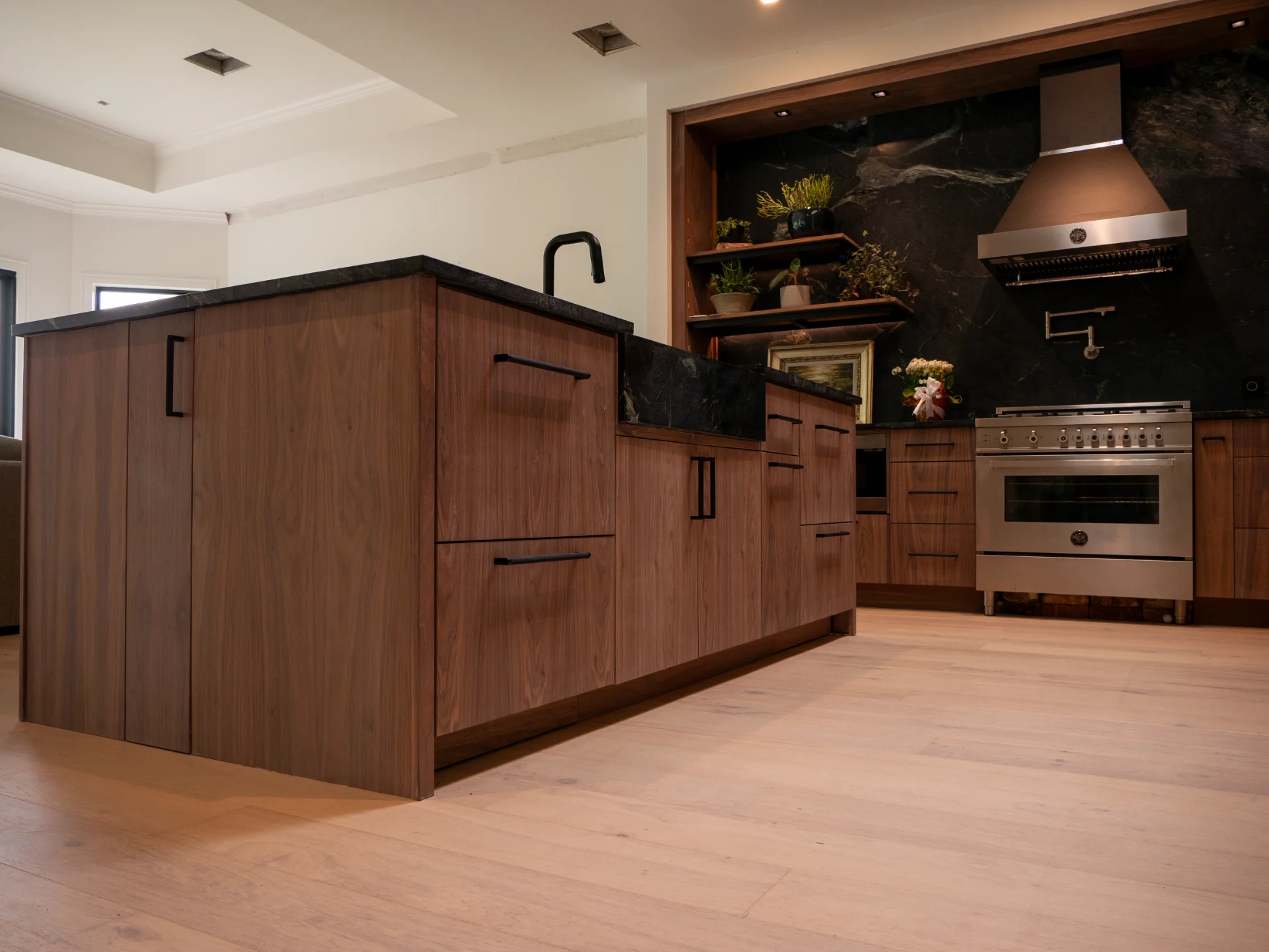 Modern grain-matched walnut kitchen in Austin, West Lake Hills, featuring a green soapstone backsplash, stainless steel range, and minimalist island cabinetry. - Detail 7