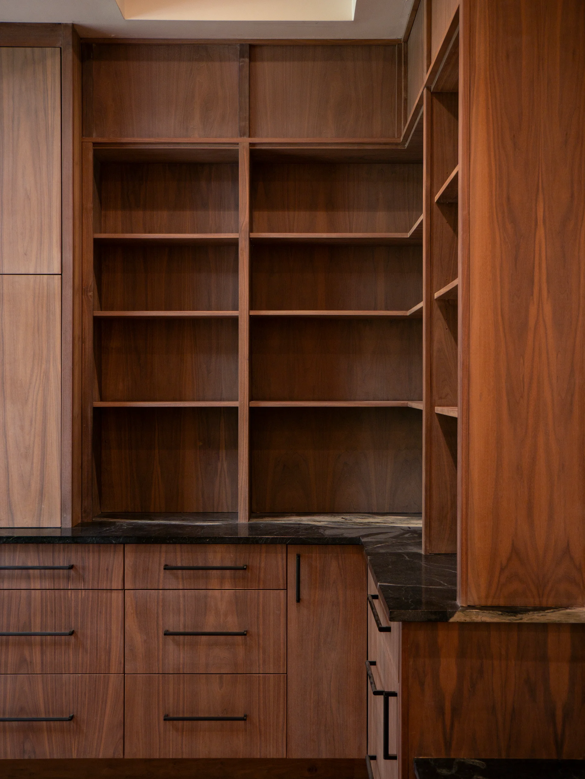 Modern grain-matched walnut kitchen in Austin, West Lake Hills, featuring a green soapstone backsplash, stainless steel range, and minimalist island cabinetry. - Detail 4