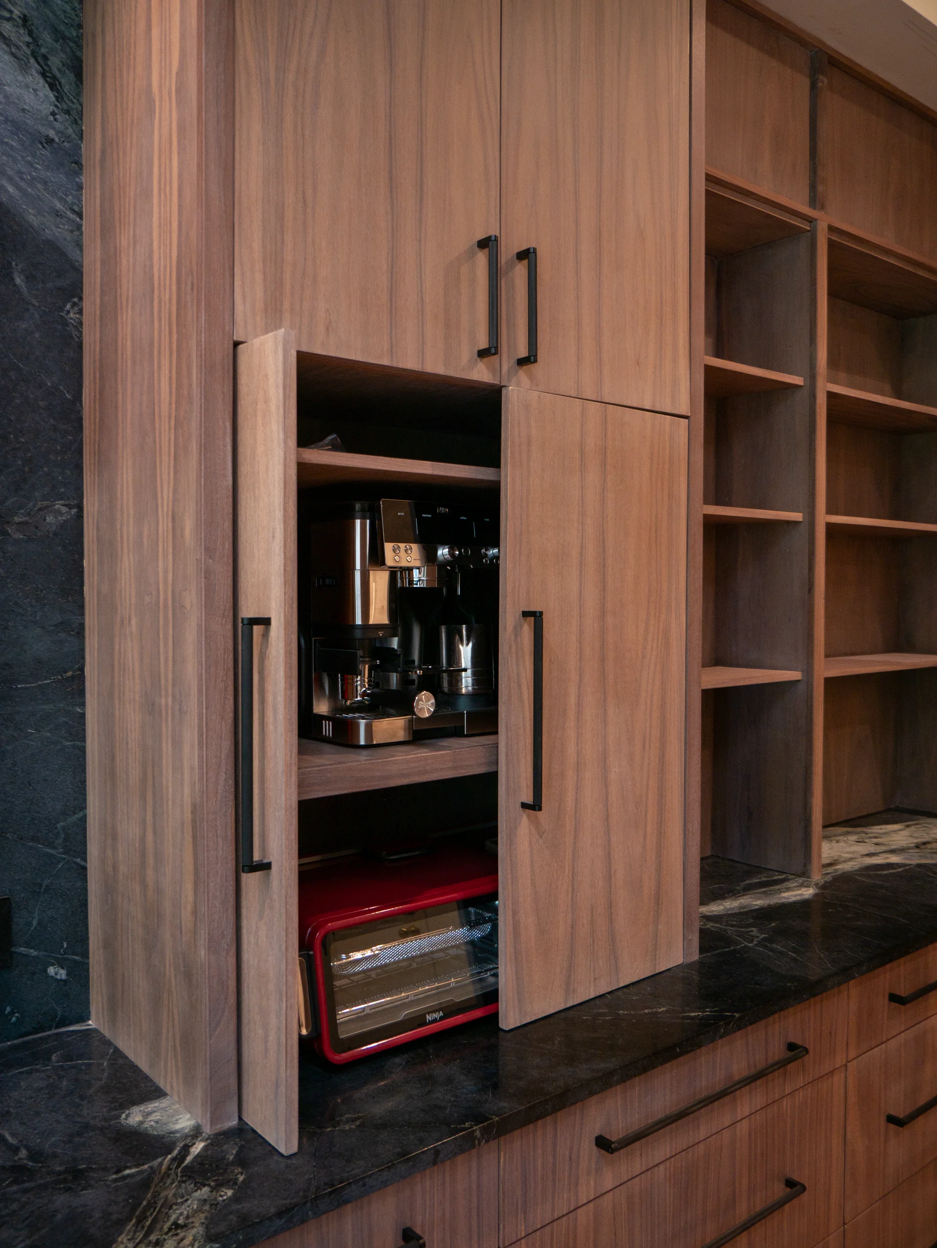 Modern grain-matched walnut kitchen in Austin, West Lake Hills, featuring a green soapstone backsplash, stainless steel range, and minimalist island cabinetry. - Detail 8