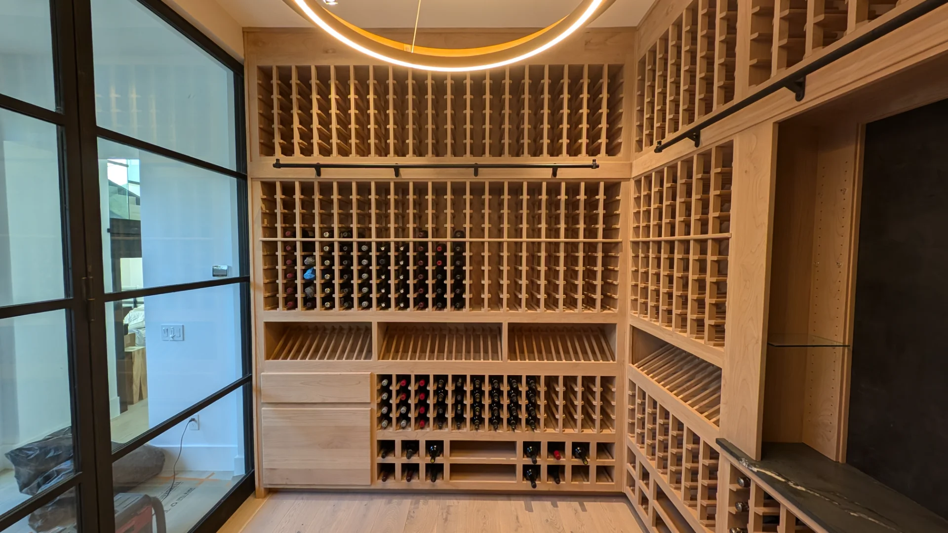 Modern custom-built wooden wine cellar in a West Lake Hills home, featuring floor-to-ceiling wine racks, a rolling wooden ladder, and glass-paneled doors as part of the New Project in Austin, Texas. - Detail 2