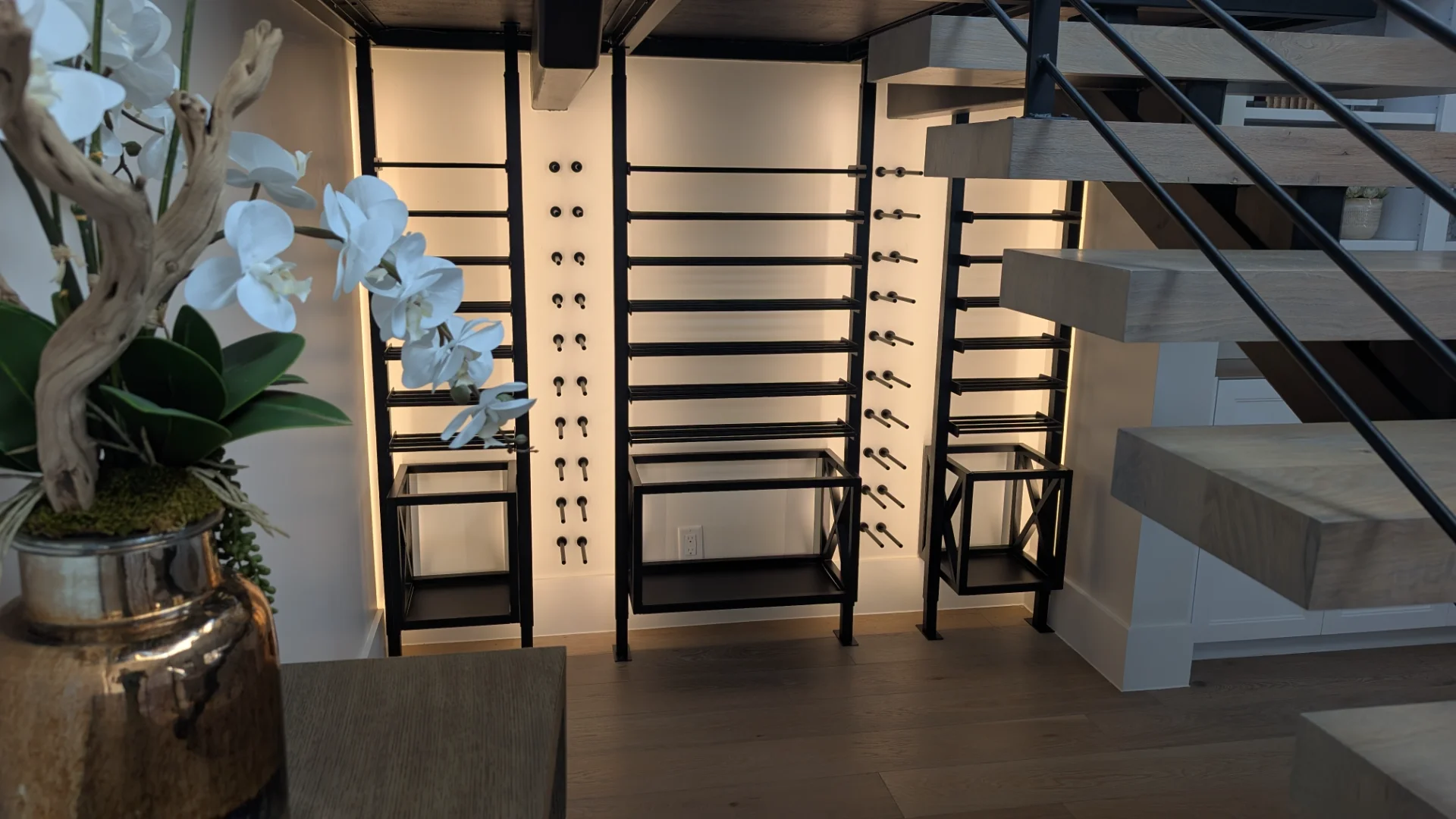 A custom-designed modern black metal wine rack with sophisticated backlighting, installed in a luxury home bar area in Austin, featuring dark wood ceiling beams and sleek cabinetry. - Detail 2