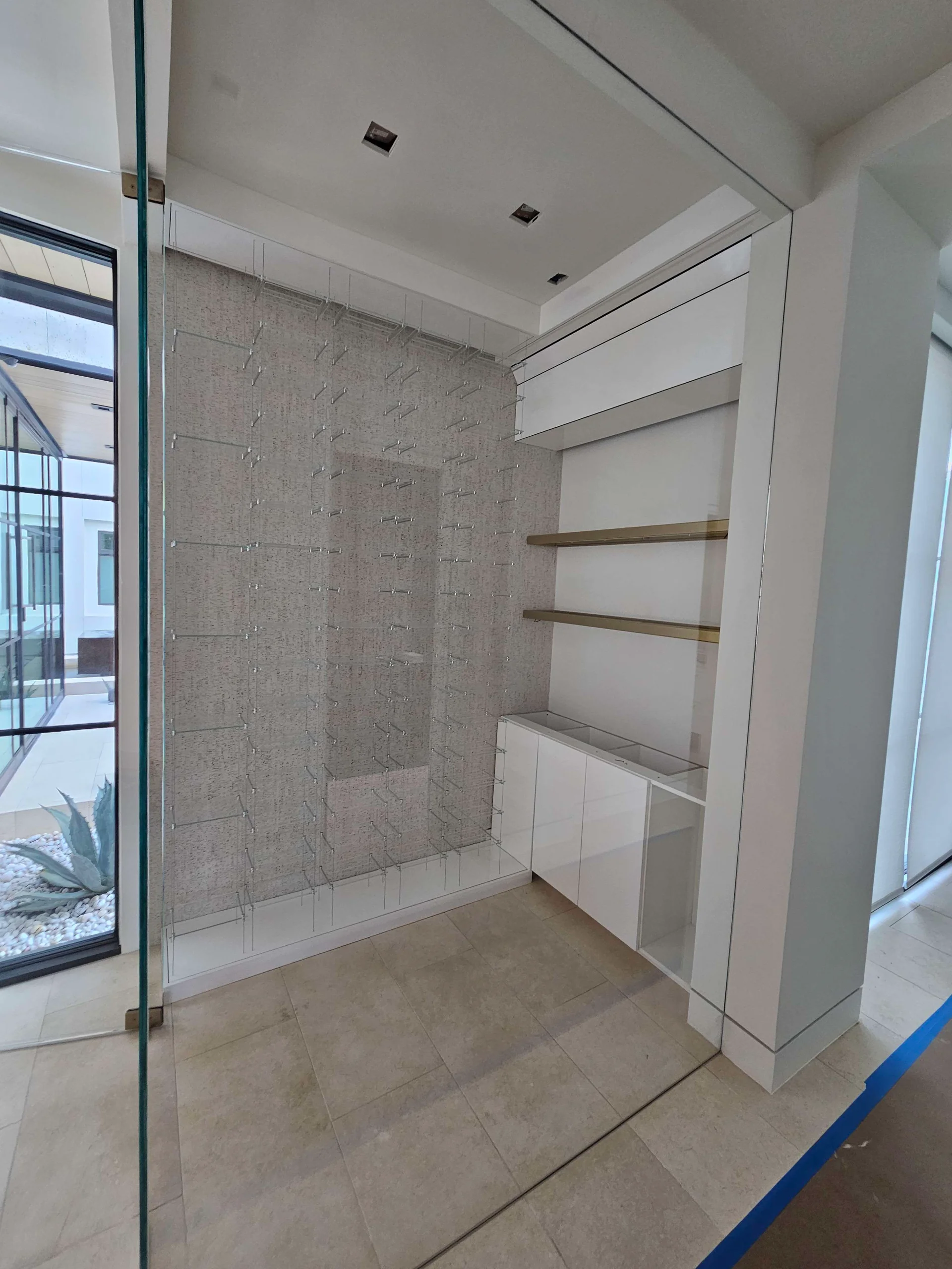 A sleek modern wine cellar under construction in West Lake Hills, Austin, showcasing custom glass bottle racks and elegant gold floating shelves for a New Project in the Texas Hill Country. - Detail 3