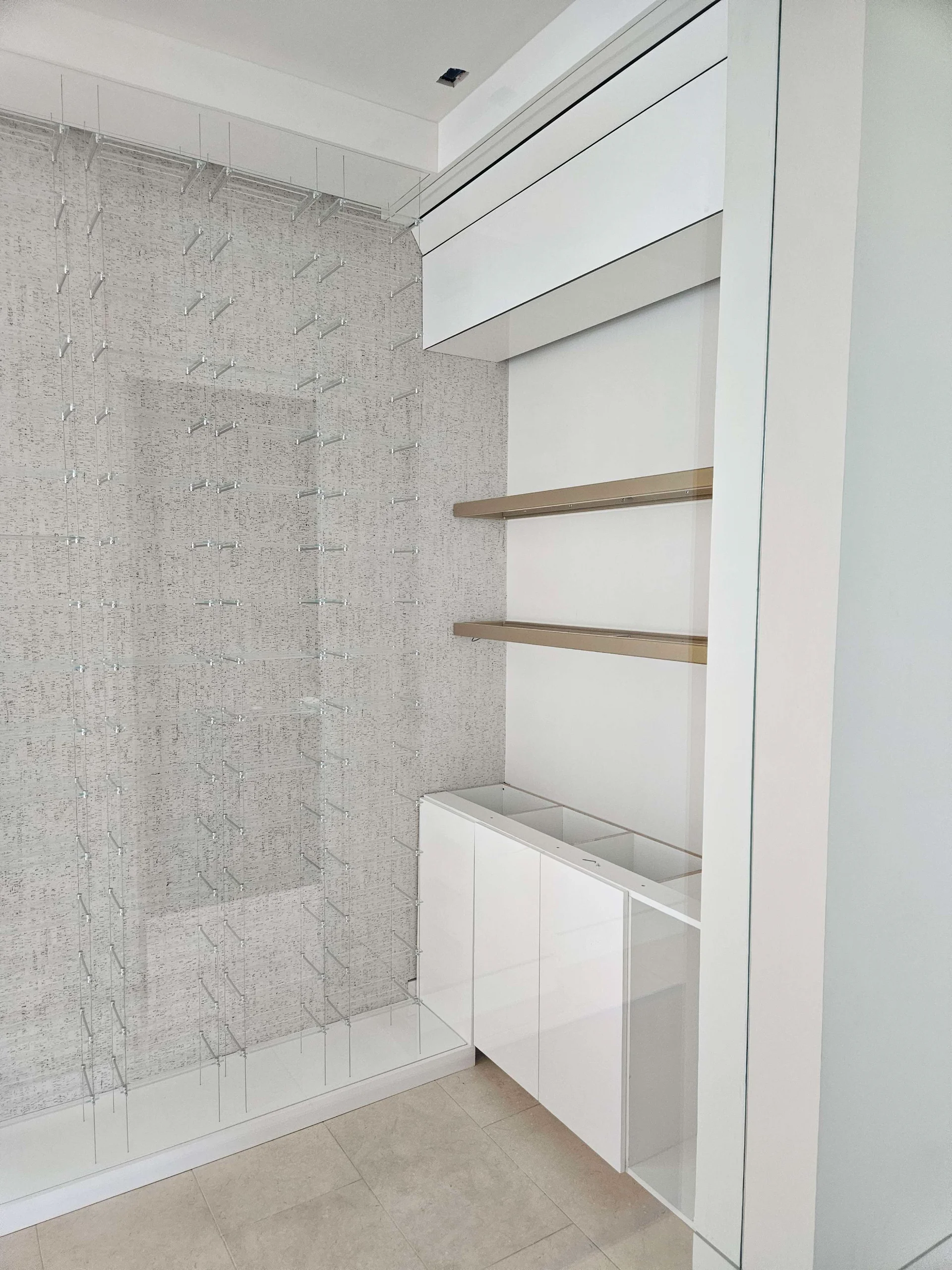 A sleek modern wine cellar under construction in West Lake Hills, Austin, showcasing custom glass bottle racks and elegant gold floating shelves for a New Project in the Texas Hill Country. - Detail 2