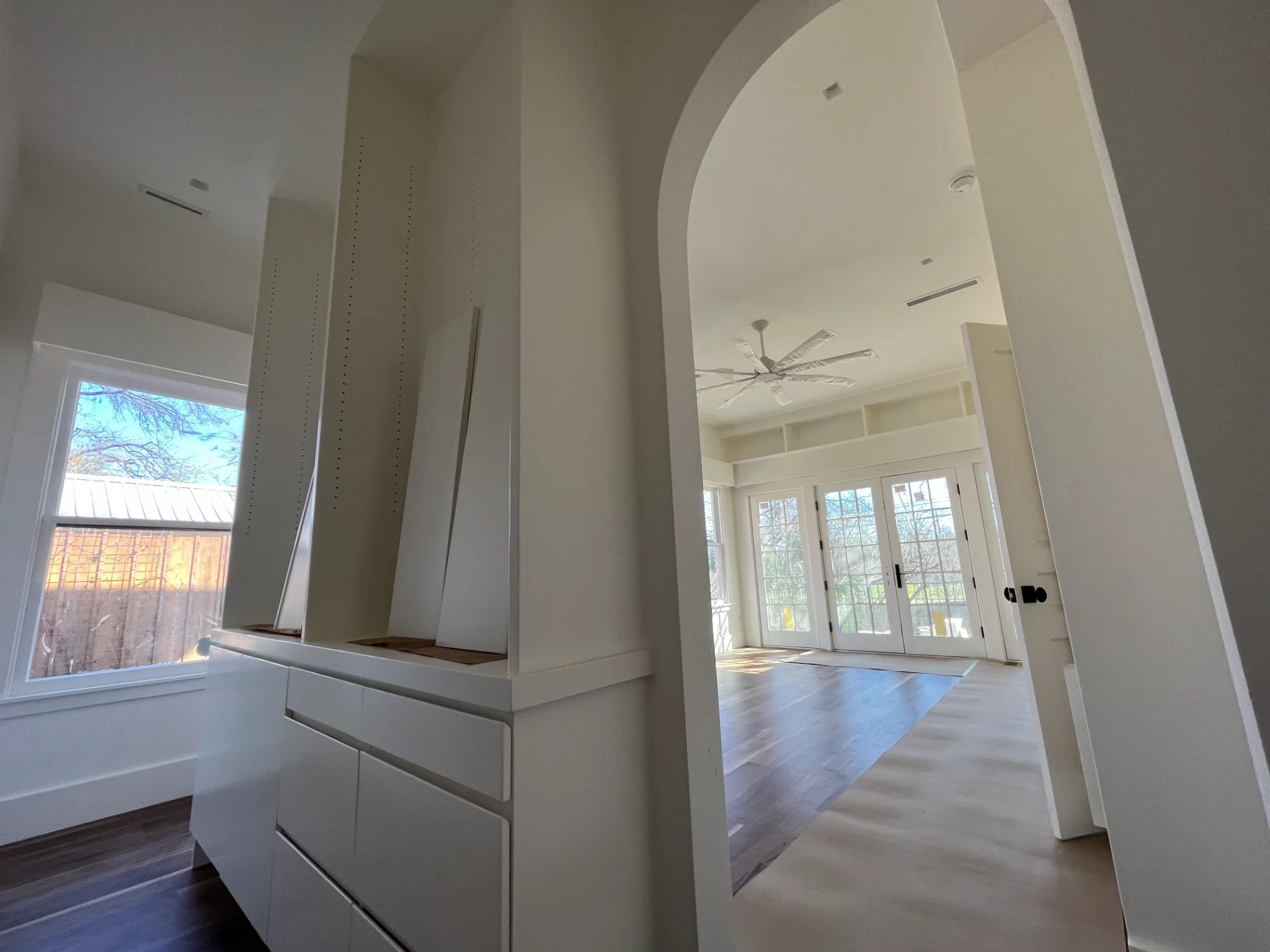 Modern custom home interior in West Lake Hills, Austin, featuring elegant hardwood floors, built-in floating shelves, a bright skylight, and a white ceiling fan. - Detail 2