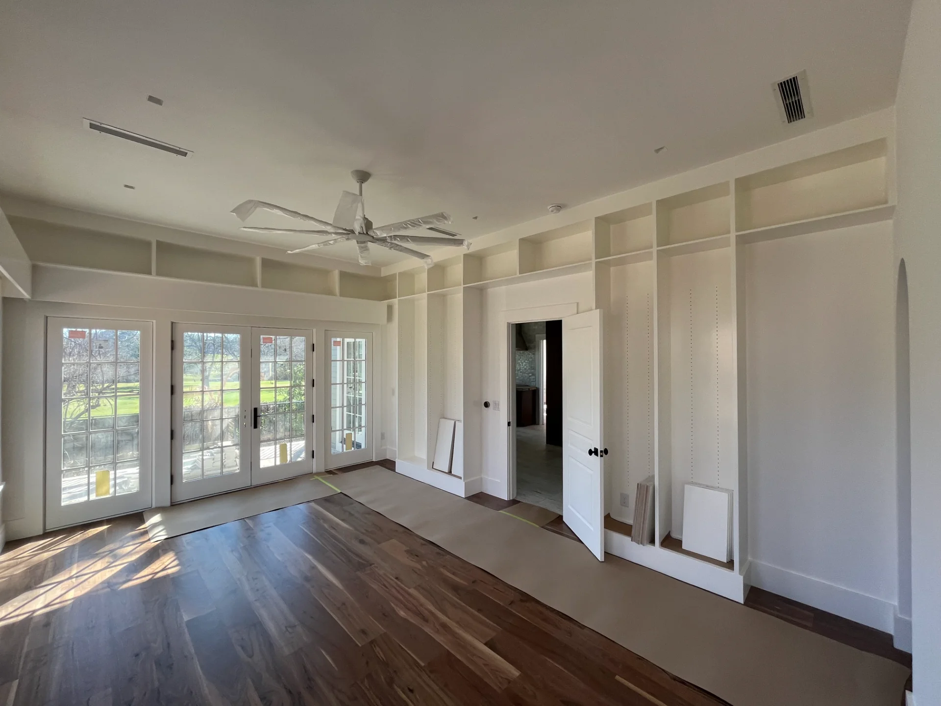 Modern custom home interior in West Lake Hills, Austin, featuring elegant hardwood floors, built-in floating shelves, a bright skylight, and a white ceiling fan. - Detail 3