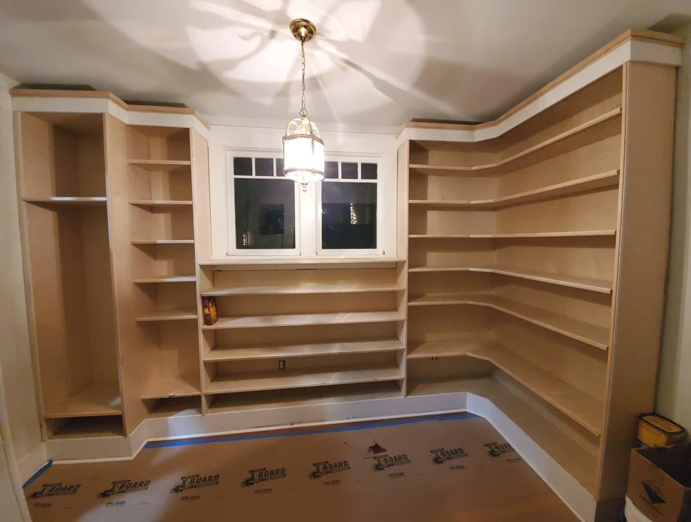 A luxurious custom walk-in closet with floor-to-ceiling white built-in shelving, a hanging rod, dark wood flooring, and a decorative gold lantern light fixture in an Austin, Texas Hill Country home. - Detail 2