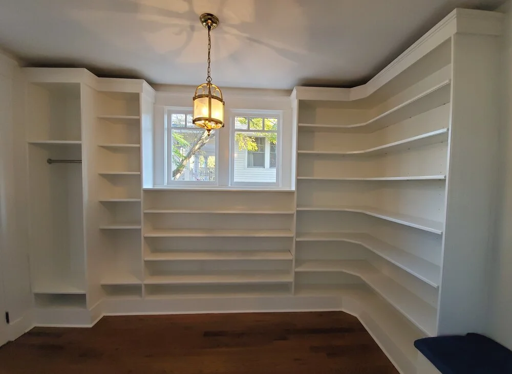A luxurious custom walk-in closet with floor-to-ceiling white built-in shelving, a hanging rod, dark wood flooring, and a decorative gold lantern light fixture in an Austin, Texas Hill Country home. - Detail 3