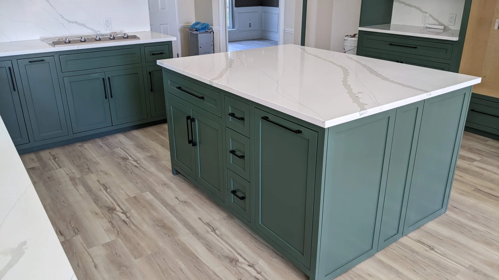 A modern two-tone kitchen remodel in Austin, Texas, showcasing off-white upper cabinets and deep teal lower cabinets with black hardware. The design features marble-patterned quartz countertops and backsplash, a central island, and recessed lighting in a Tarrytown home. - Detail 8