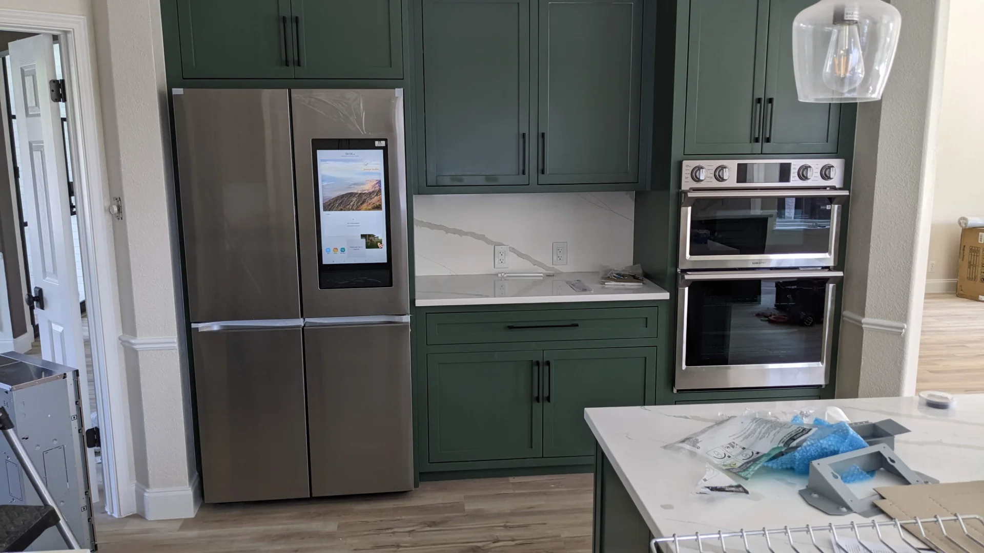 A modern two-tone kitchen remodel in Austin, Texas, showcasing off-white upper cabinets and deep teal lower cabinets with black hardware. The design features marble-patterned quartz countertops and backsplash, a central island, and recessed lighting in a Tarrytown home. - Detail 9