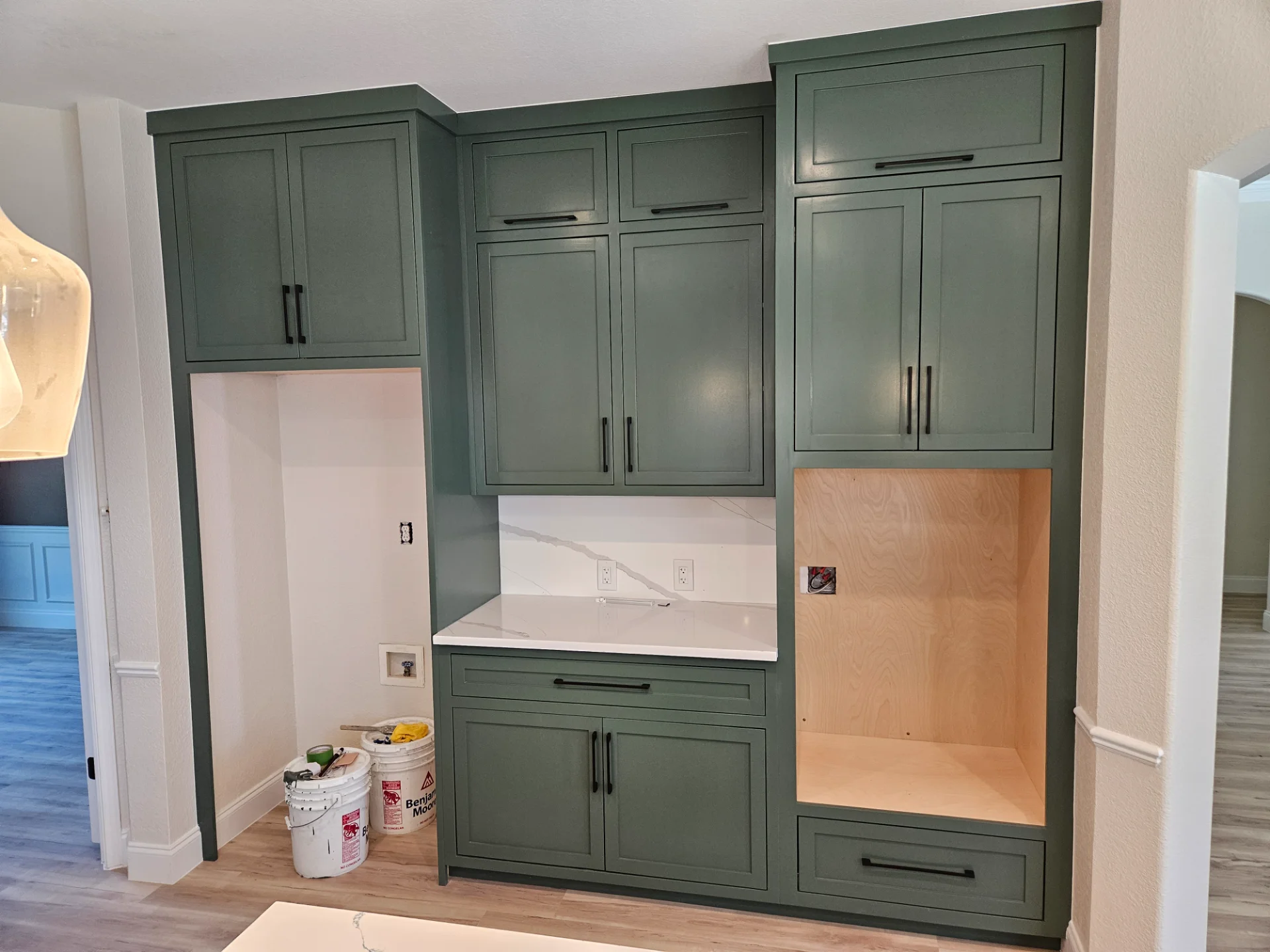 A modern two-tone kitchen remodel in Austin, Texas, showcasing off-white upper cabinets and deep teal lower cabinets with black hardware. The design features marble-patterned quartz countertops and backsplash, a central island, and recessed lighting in a Tarrytown home. - Detail 3