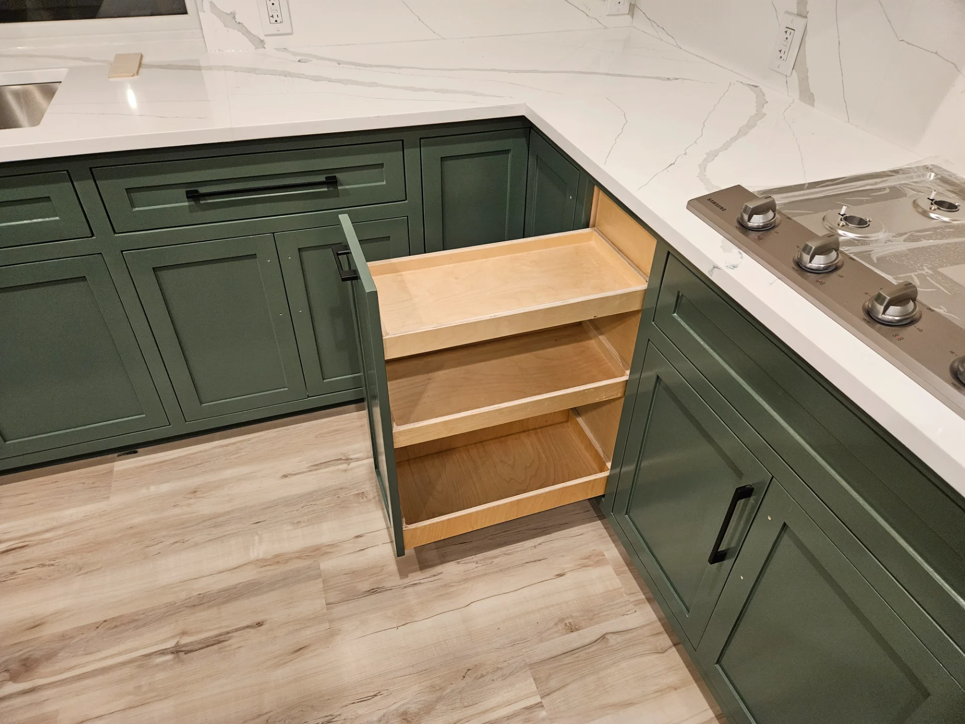 A modern two-tone kitchen remodel in Austin, Texas, showcasing off-white upper cabinets and deep teal lower cabinets with black hardware. The design features marble-patterned quartz countertops and backsplash, a central island, and recessed lighting in a Tarrytown home. - Detail 4