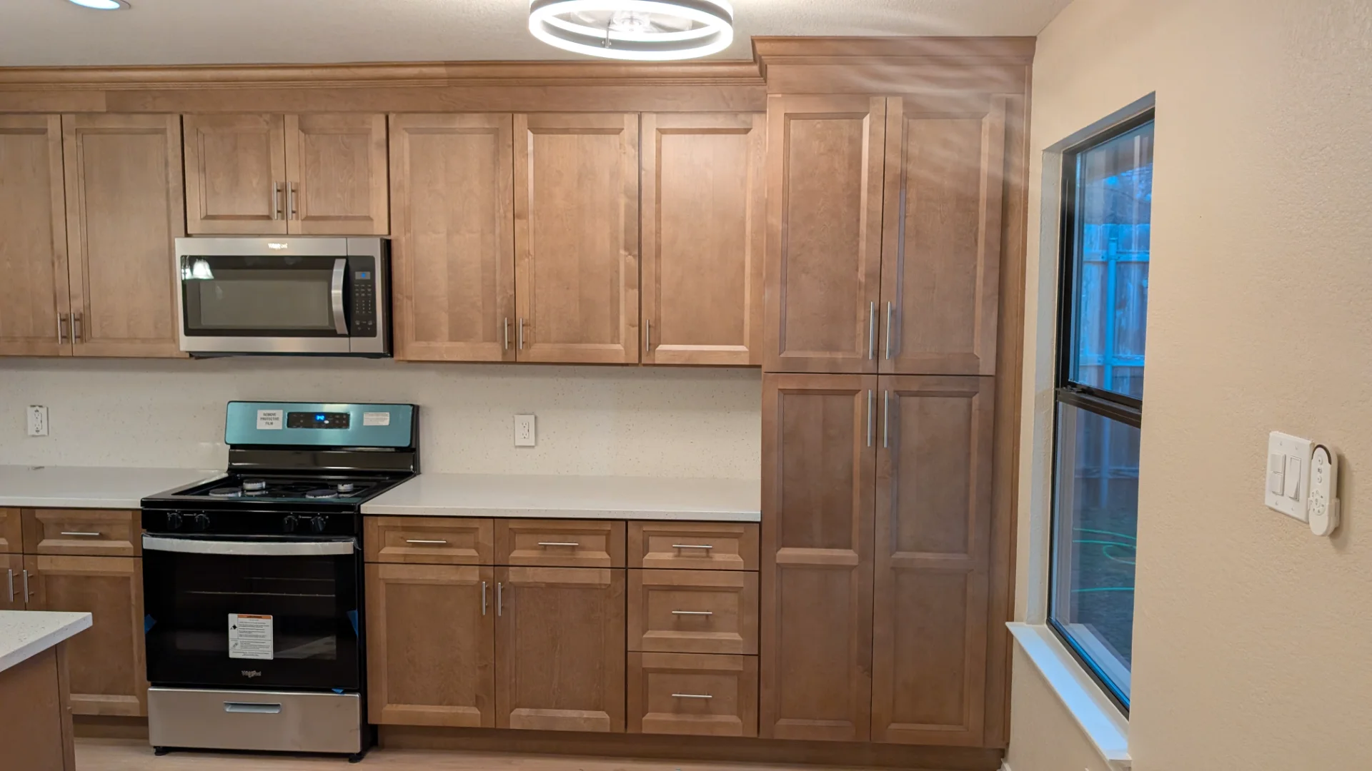 A newly completed modern kitchen remodel in Austin, Texas, featuring custom wood shaker cabinets, a large white quartz waterfall island with a sink, and stainless steel appliances. - Detail 3