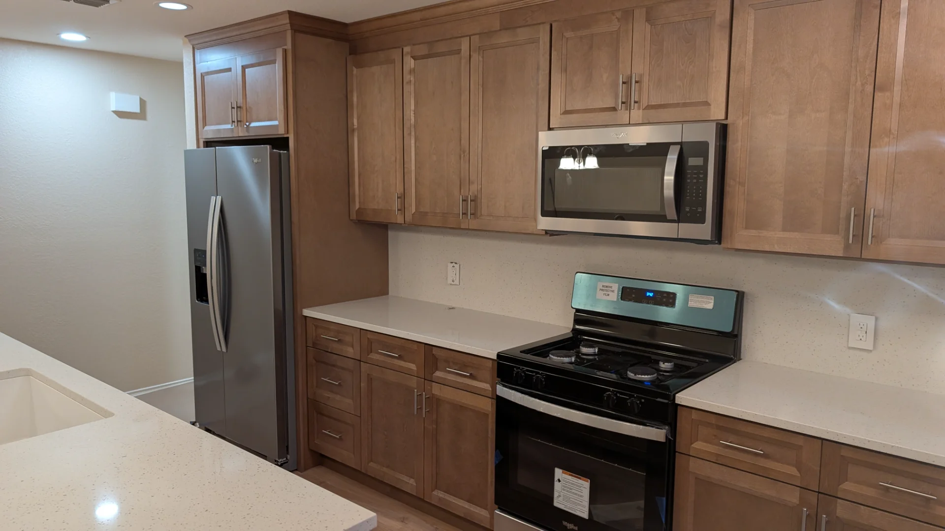 A newly completed modern kitchen remodel in Austin, Texas, featuring custom wood shaker cabinets, a large white quartz waterfall island with a sink, and stainless steel appliances. - Detail 4
