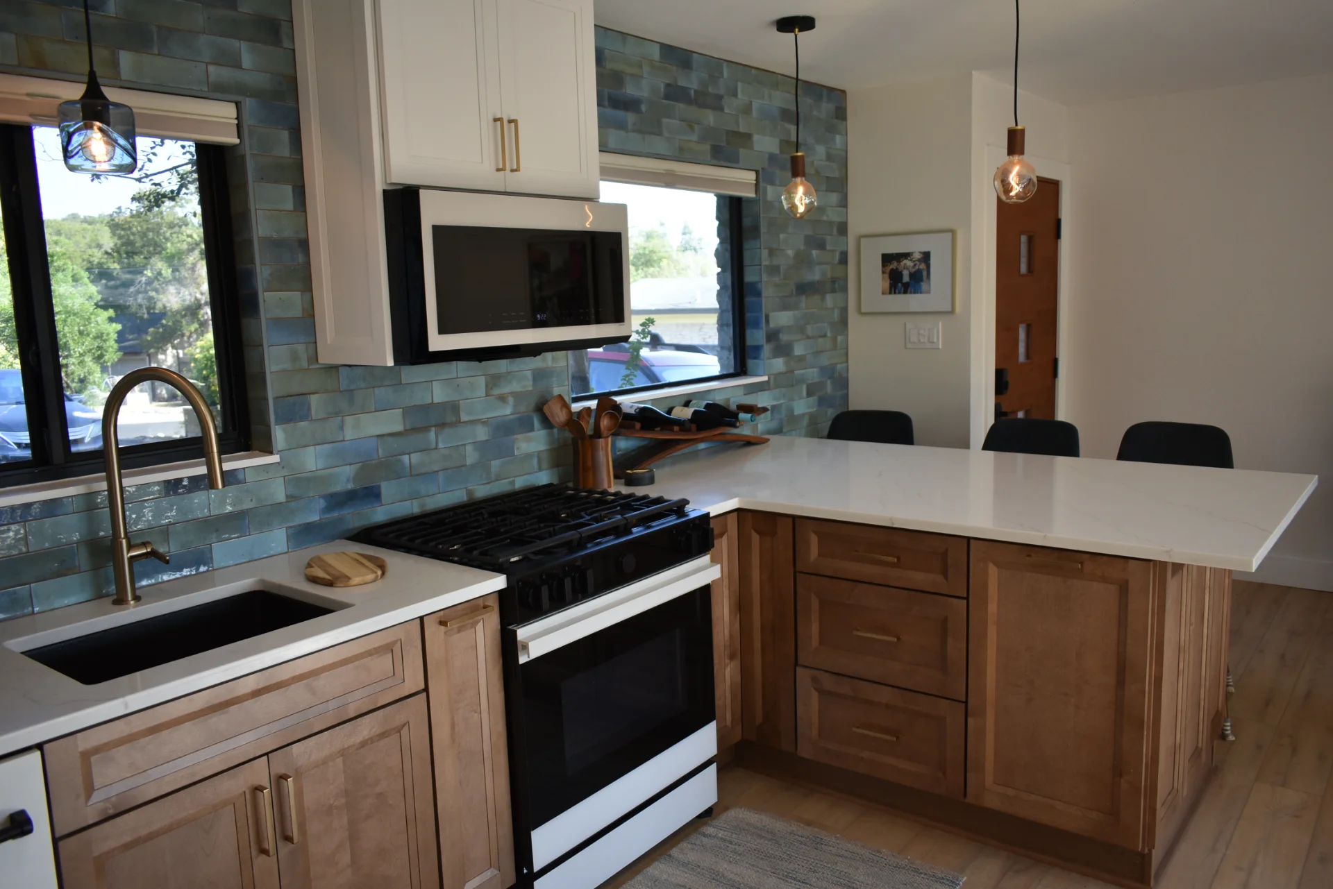 Modern kitchen from New Project in Austin, TX, featuring a bold blue subway tile backsplash, white and wood cabinetry, a large kitchen island with seating, and gold accents. This contemporary design is perfect for homes in West Lake Hills, Dripping Springs, and Tarrytown. - Detail 3