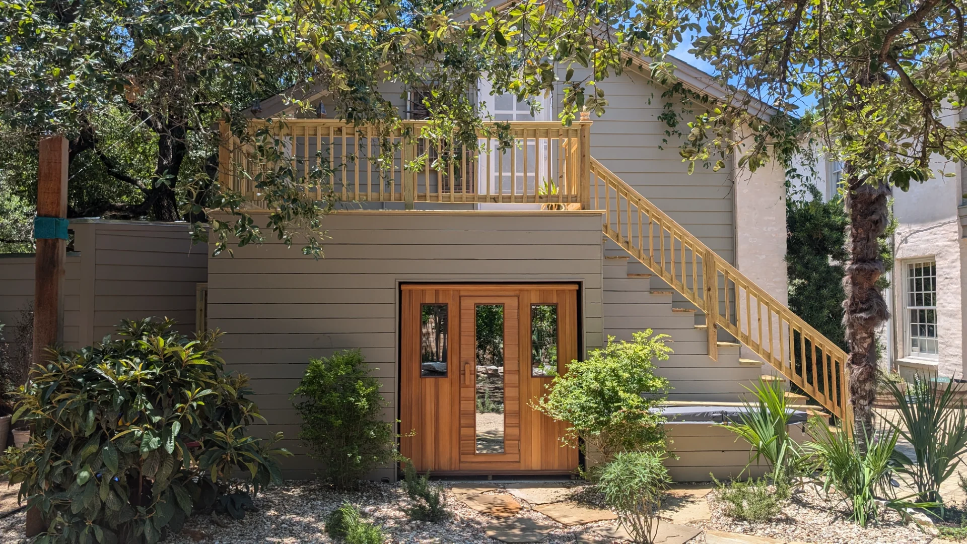 A modern outdoor sauna constructed from warm-toned wood, featuring a central door and two side panels with vertical windows, integrated into the architecture of a home in West Lake Hills, Austin. - Detail 2