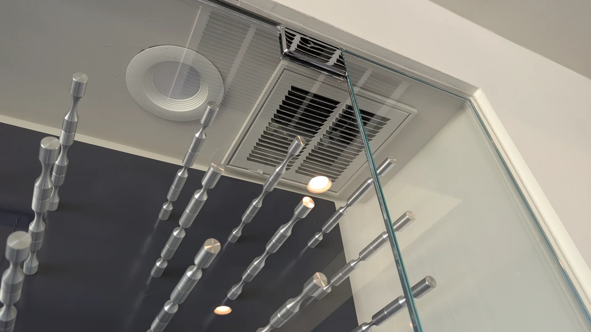 A modern, glass-enclosed wine cellar display with sleek chrome pegs against a dark navy background, set above a dark wood buffet cabinet in a luxury Austin, Texas home. - Detail 3