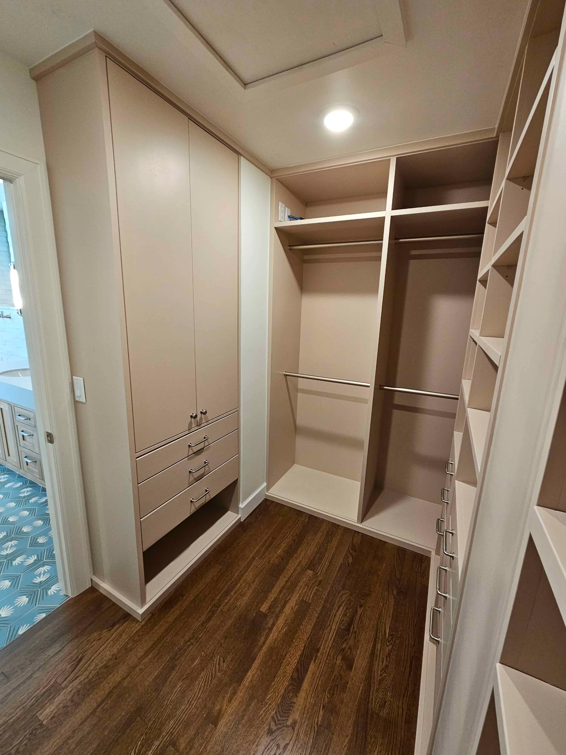 Spacious custom walk-in closet featuring floor-to-ceiling beige cabinetry with open shelving and integrated drawers, set against dark wood floors in a Tarrytown, Austin home. - Detail 2