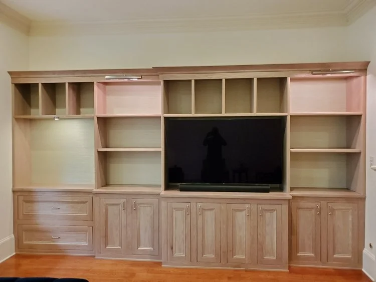 Custom light wood built-in entertainment center and shelving unit featuring integrated lighting, framed art, and decorative accents in a modern Austin home. - Detail 3