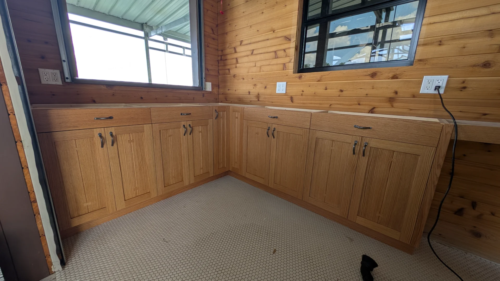 Interior view of a luxury artisan oak boat dock storage suite in West Lake Hills, Texas, featuring custom craftsman cabinetry, quartz countertops, and a scenic lakefront window next to a docked boat. - Detail 3