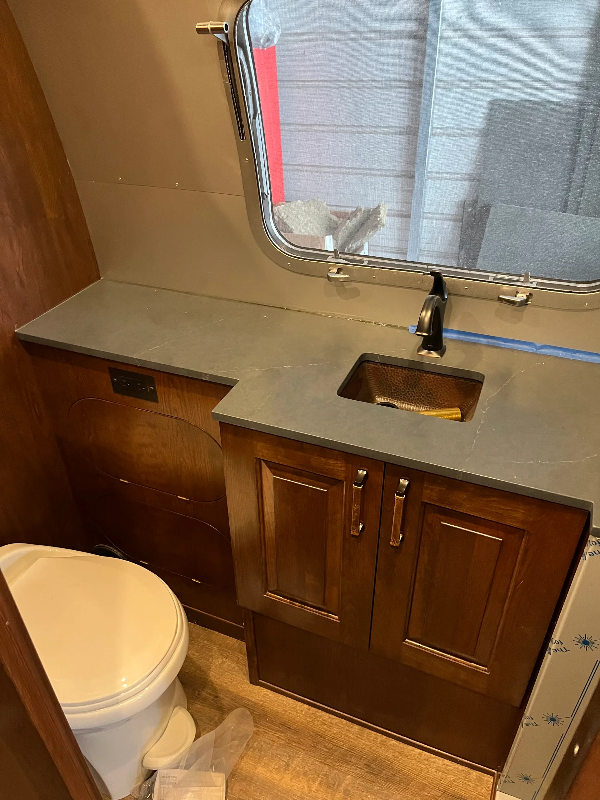 Modern interior of a renovated Airstream featuring custom light-wood cabinetry, a sleek black kitchenette, and wood-style flooring in a New Project located in Austin and the Texas Hill Country. - Detail 5