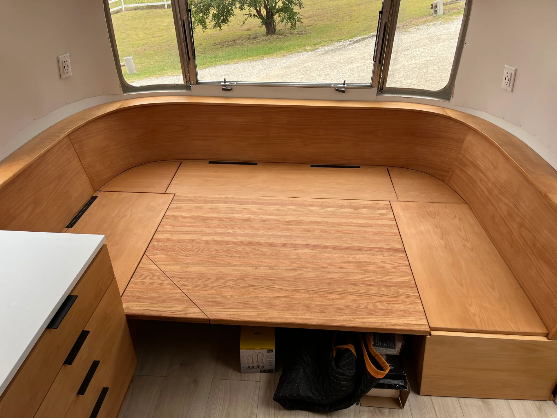 Modern interior of a renovated Airstream featuring custom light-wood cabinetry, a sleek black kitchenette, and wood-style flooring in a New Project located in Austin and the Texas Hill Country. - Detail 11
