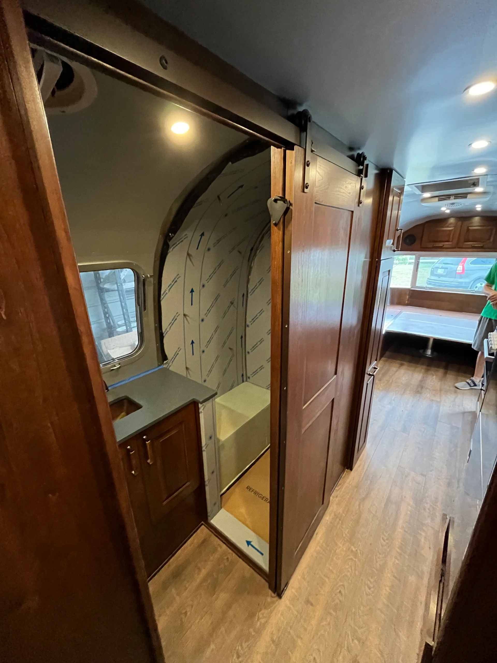 Modern interior of a renovated Airstream featuring custom light-wood cabinetry, a sleek black kitchenette, and wood-style flooring in a New Project located in Austin and the Texas Hill Country. - Detail 9