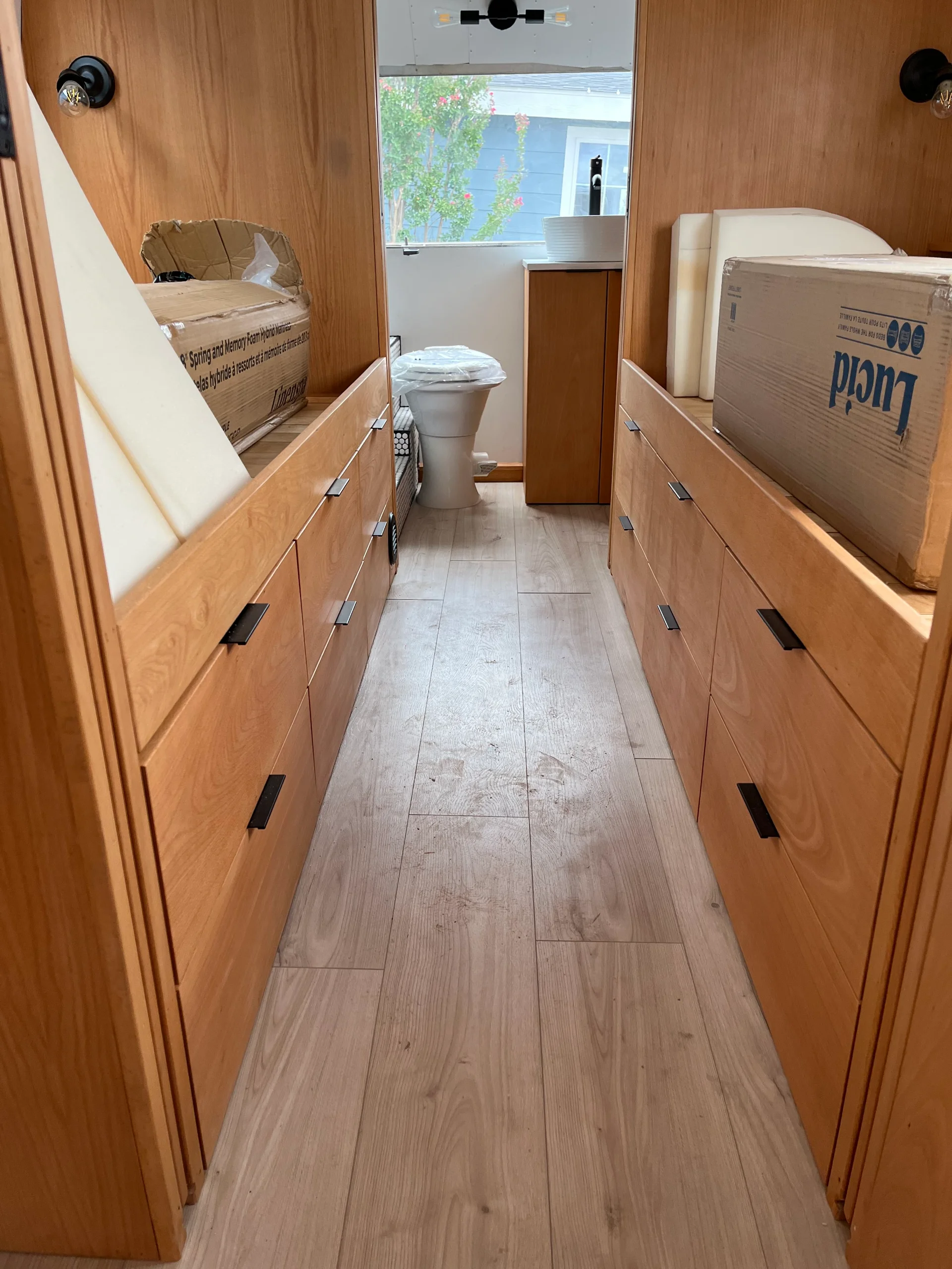 Modern interior of a renovated Airstream featuring custom light-wood cabinetry, a sleek black kitchenette, and wood-style flooring in a New Project located in Austin and the Texas Hill Country. - Detail 16