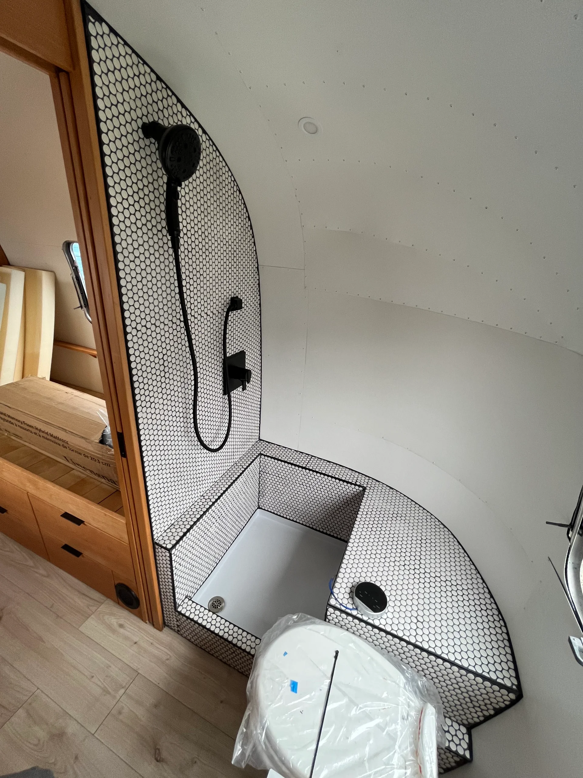 Modern interior of a renovated Airstream featuring custom light-wood cabinetry, a sleek black kitchenette, and wood-style flooring in a New Project located in Austin and the Texas Hill Country. - Detail 19