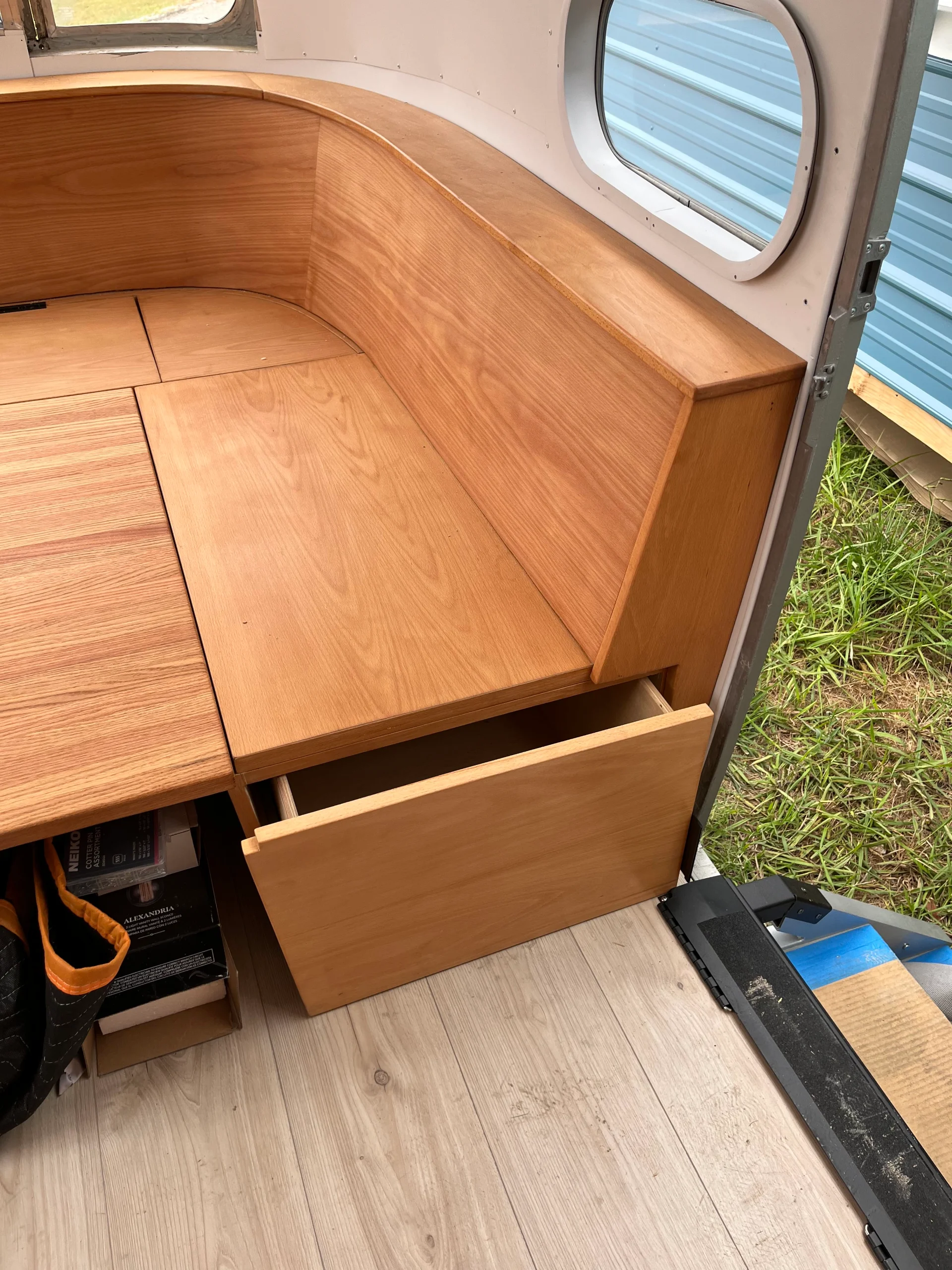 Modern interior of a renovated Airstream featuring custom light-wood cabinetry, a sleek black kitchenette, and wood-style flooring in a New Project located in Austin and the Texas Hill Country. - Detail 20