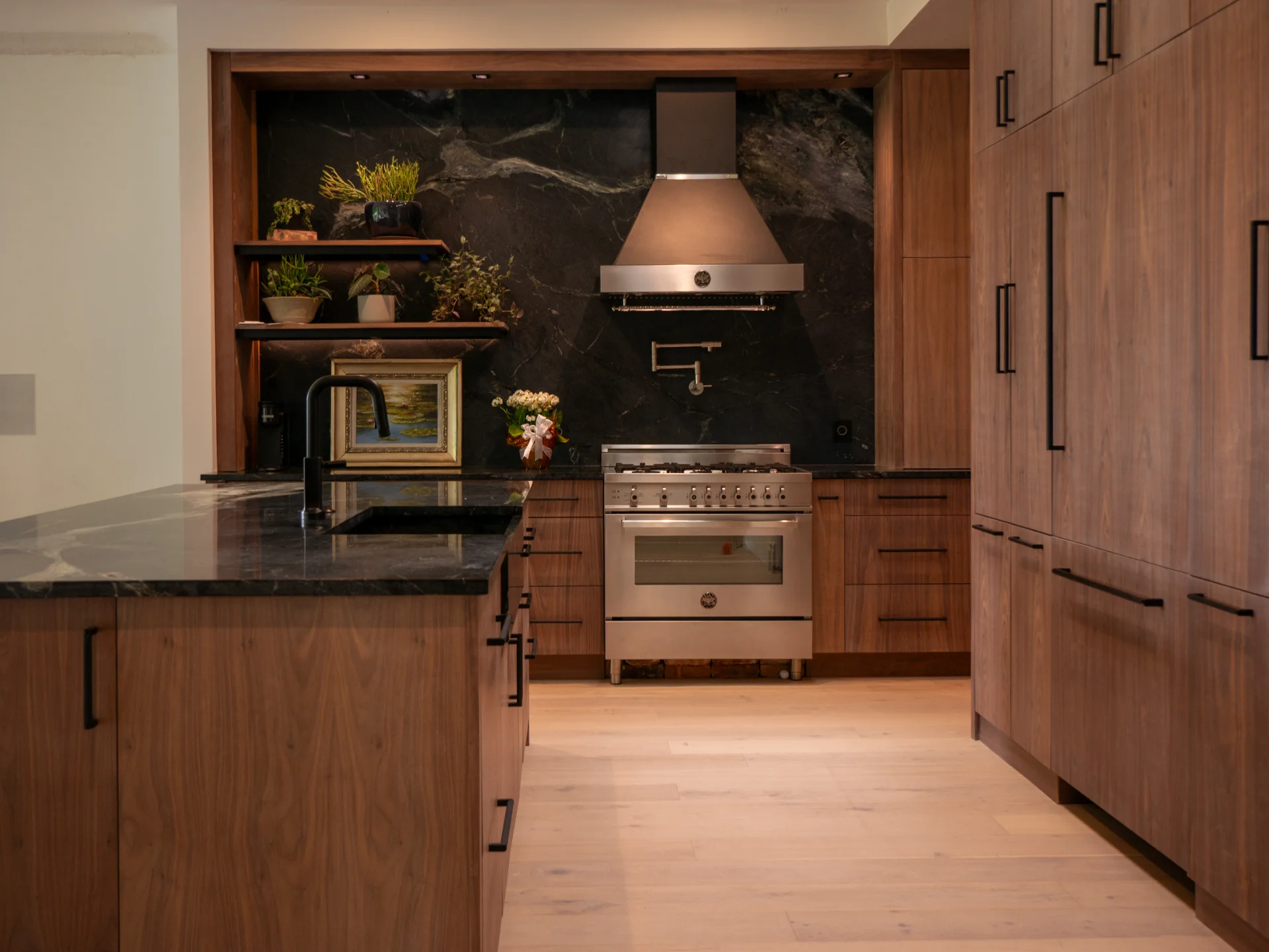 Modern grain-matched walnut kitchen in Austin, West Lake Hills, featuring a green soapstone backsplash, stainless steel range, and minimalist island cabinetry.