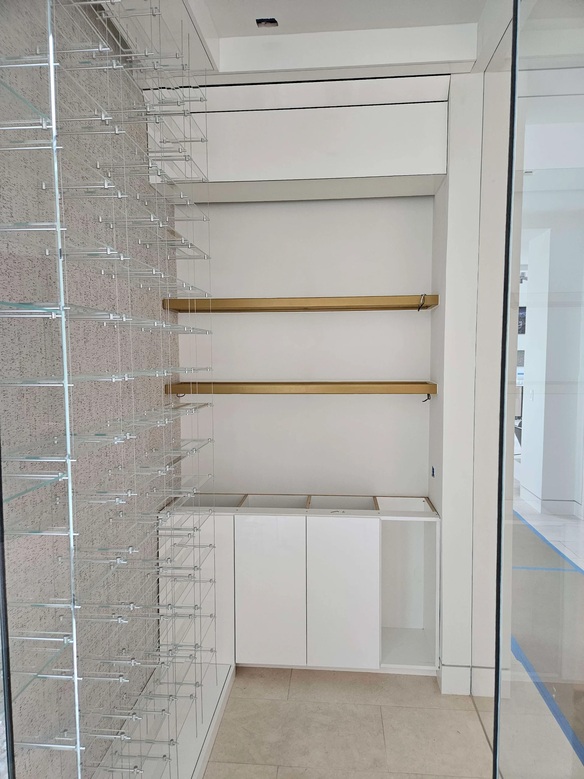 A sleek modern wine cellar under construction in West Lake Hills, Austin, showcasing custom glass bottle racks and elegant gold floating shelves for a New Project in the Texas Hill Country. - Detail 1