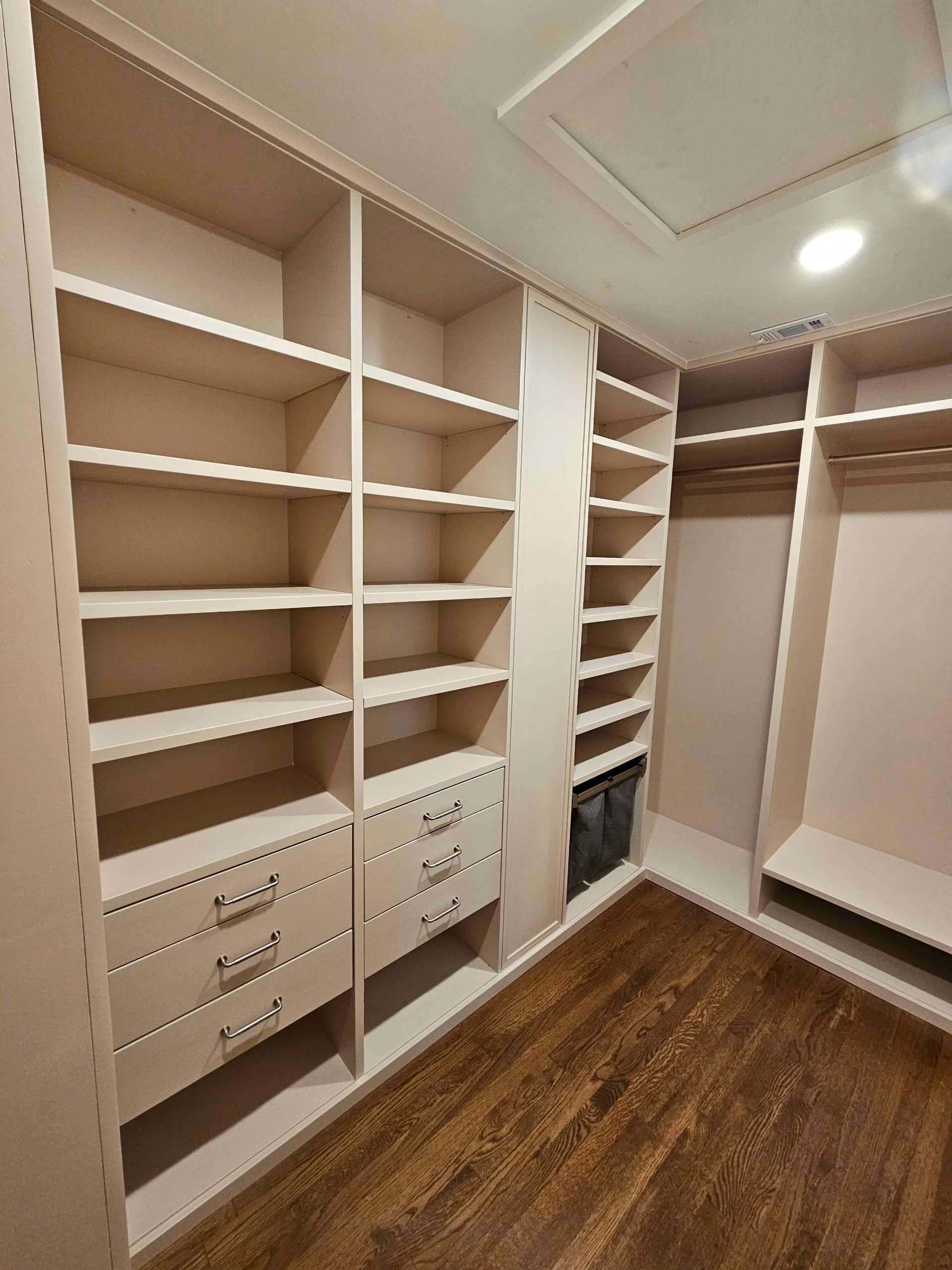 Spacious custom walk-in closet featuring floor-to-ceiling beige cabinetry with open shelving and integrated drawers, set against dark wood floors in a Tarrytown, Austin home. - Detail 1