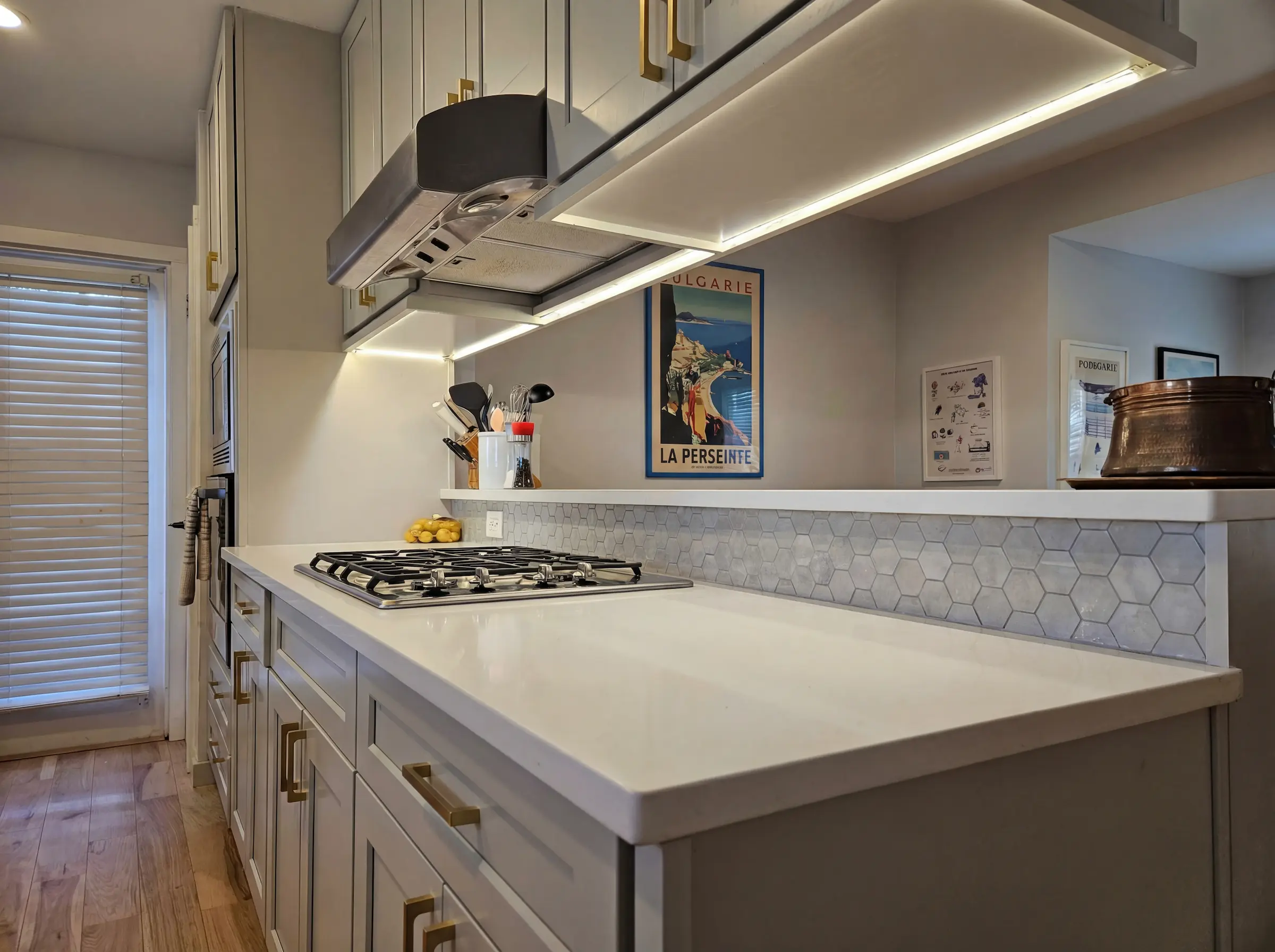 Close-up of Standard Series grey shaker cabinets featuring a smooth factory-cured enamel finish, under-cabinet lighting, and durable quartz countertops in an Austin kitchen.