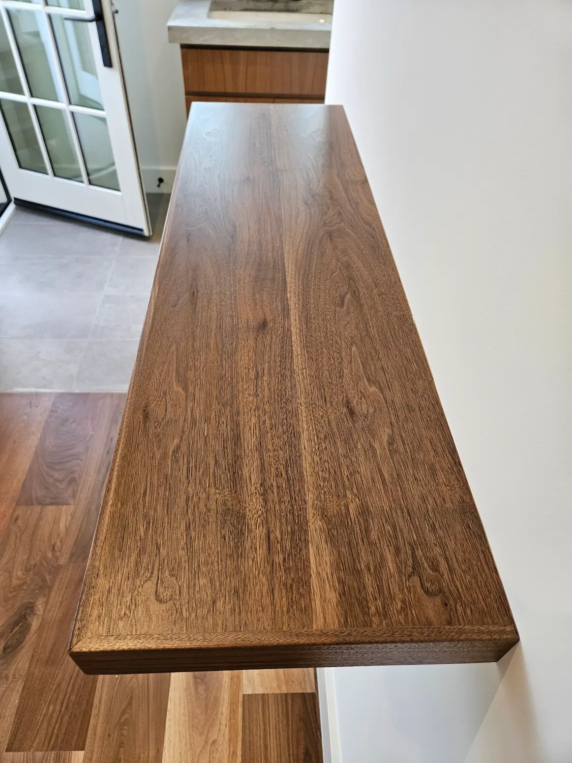 Top-down angle showcasing the rich wood grain and flawless finish of a custom fabricated walnut floating shelf.