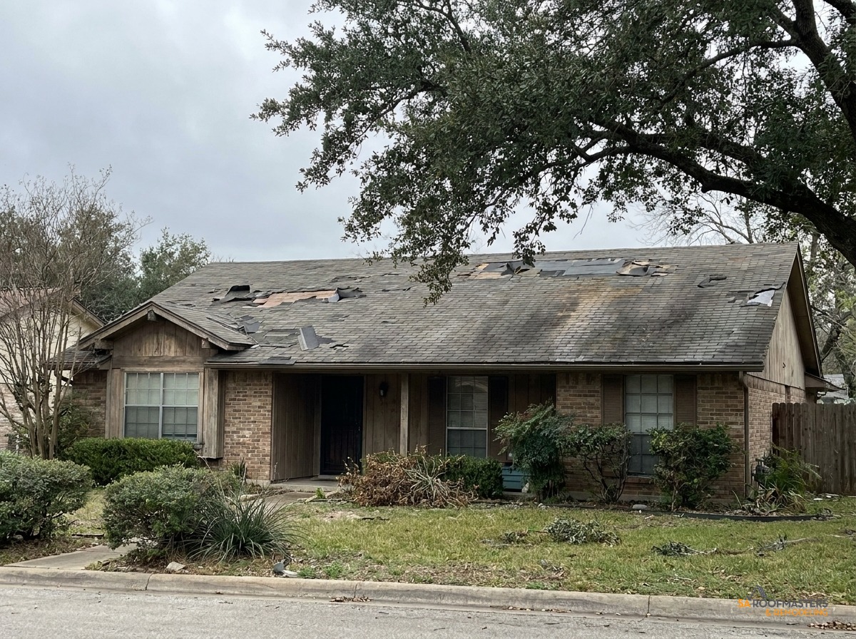 The same San Antonio home before restoration, with storm damage and missing shingles