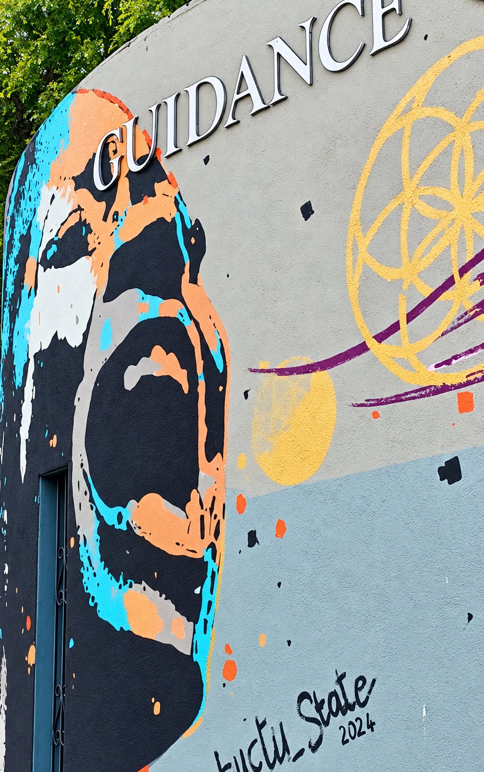 The word GUIDANCE in silver letters above a painted mural of a face turned upward, beside a gold flower-of-life.