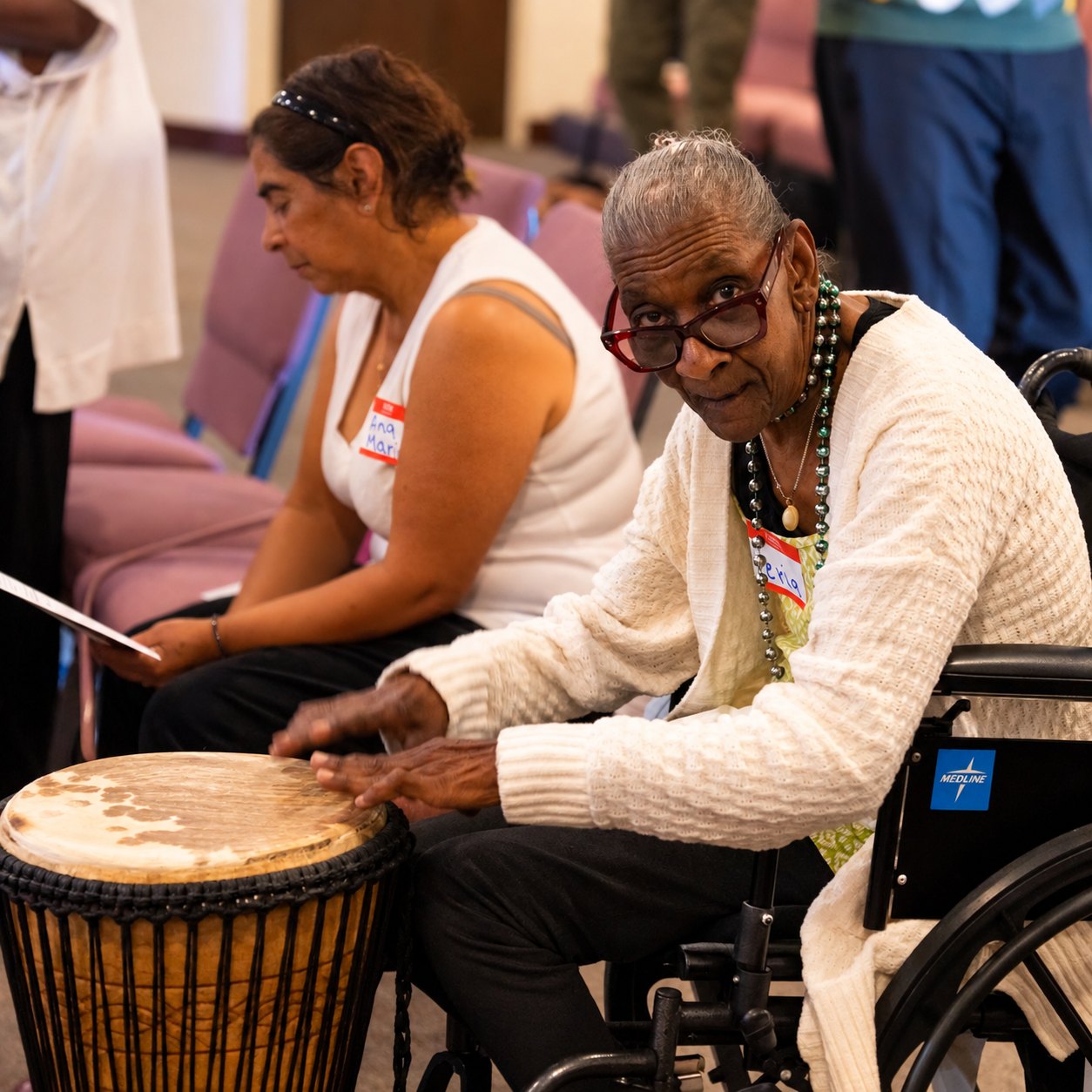 Vera, smiling as she plays a djembe drum