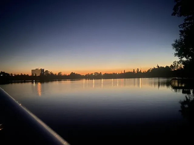 Sundhäuser See in der Dämmerung, orangefarbener Himmel spiegelt sich im ruhigen Wasser.