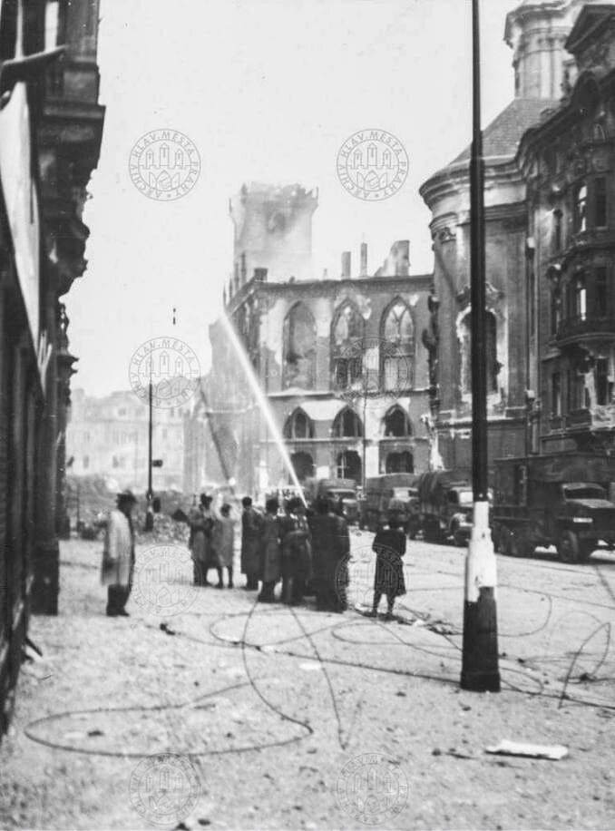 Улица Pařížská и Староместская площадь вечером 8 мая 1945 года после подписания капитуляции. Люди пытаются потушить горящие дома, из города уходят немецкие солдаты.