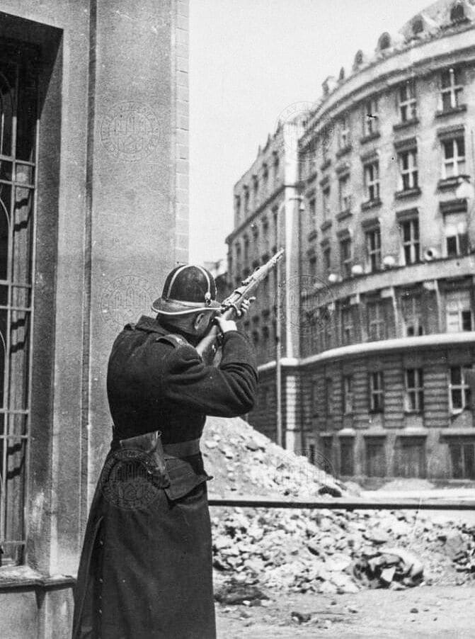 Жандарм пытается ликвидировать немецкого снайпера в неустановленном месте. 5 мая 1945 г.