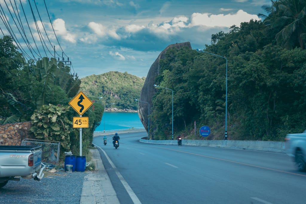 Serpentine road with sea view in Koh Samui, surrounded by lush greenery.