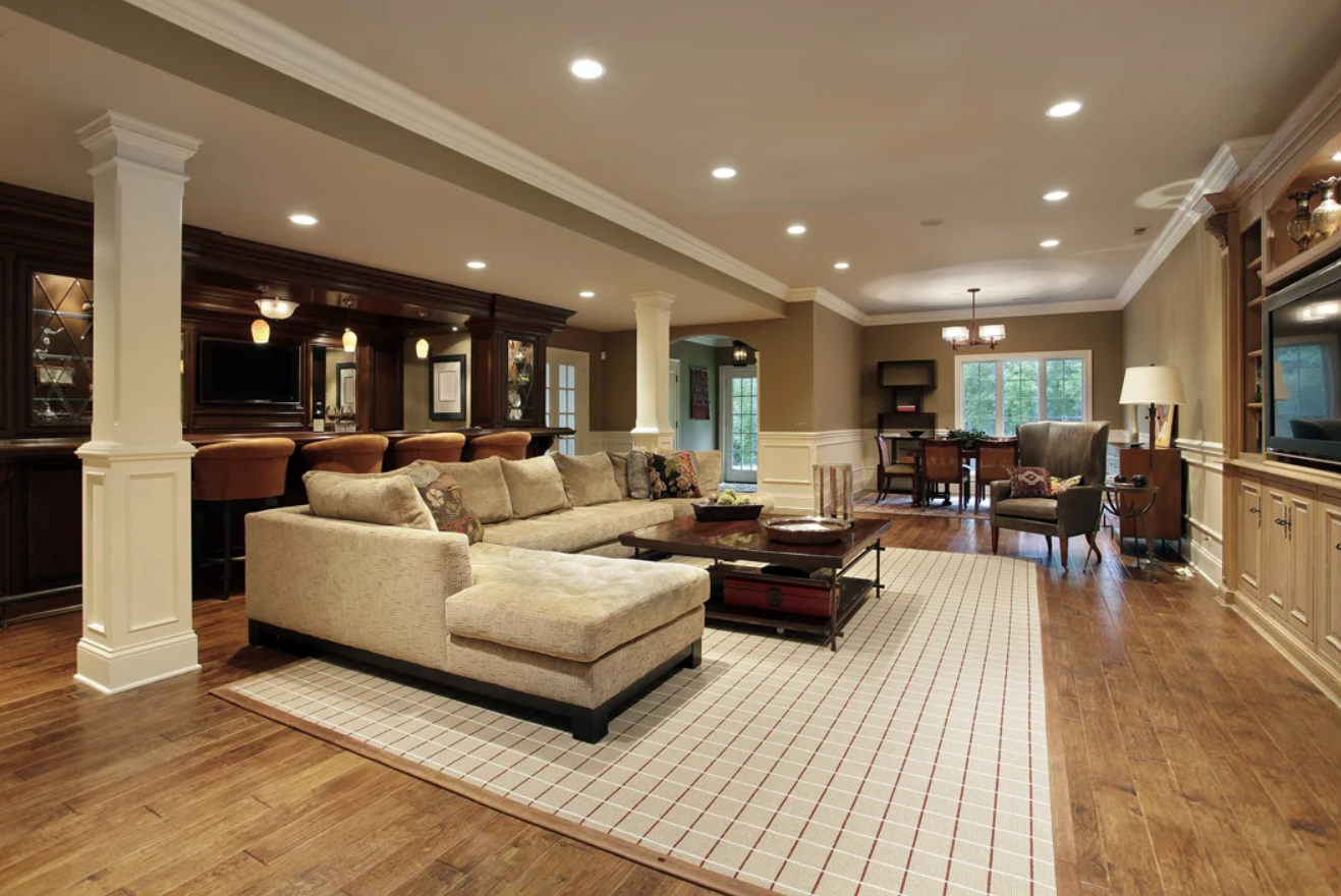High-end finished basement with a wet bar, built-in cabinetry, columns and hardwood floors