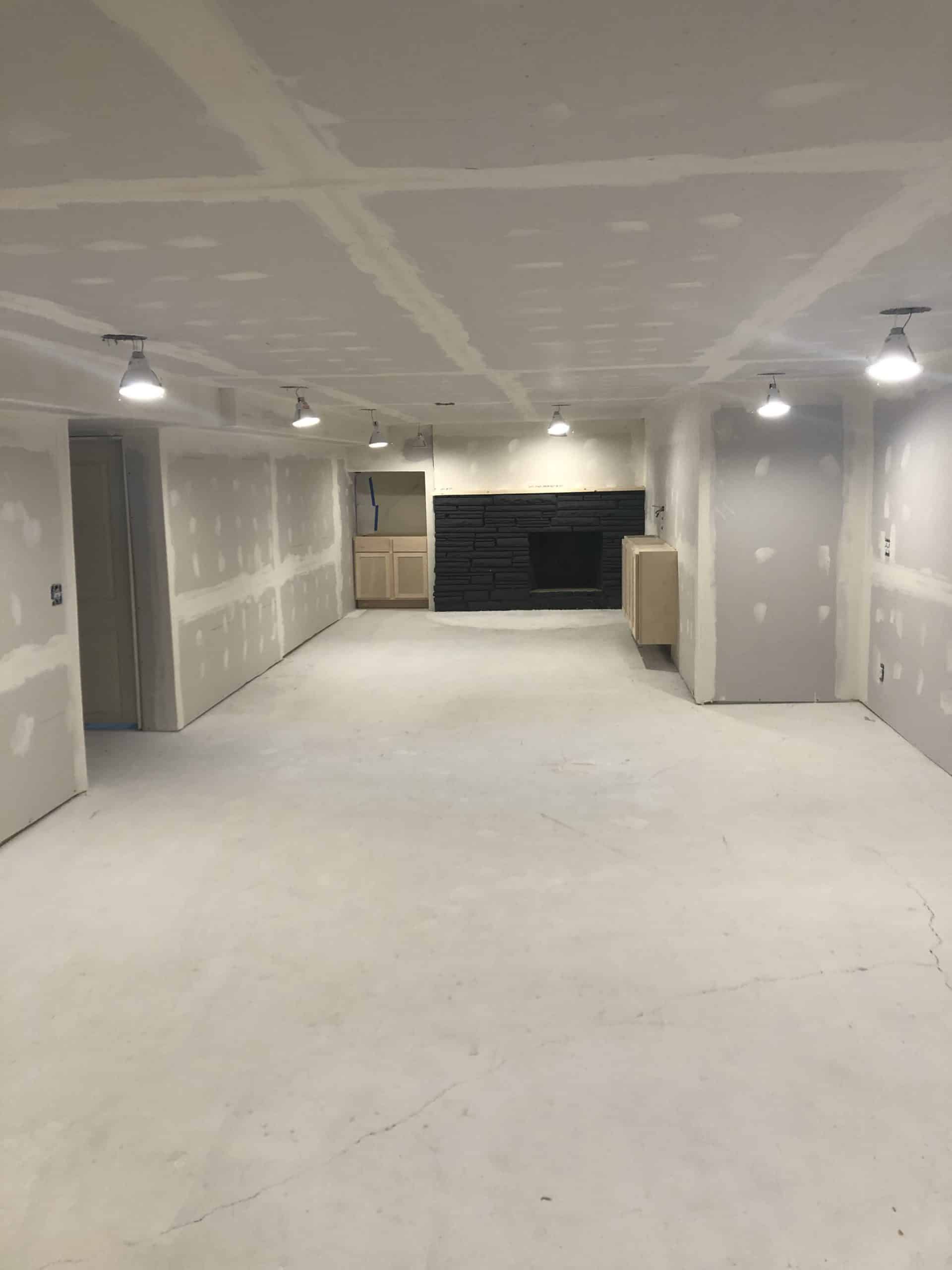 Basement finishing mid-project: drywall hung and taped, lights installed, cabinets waiting to go in