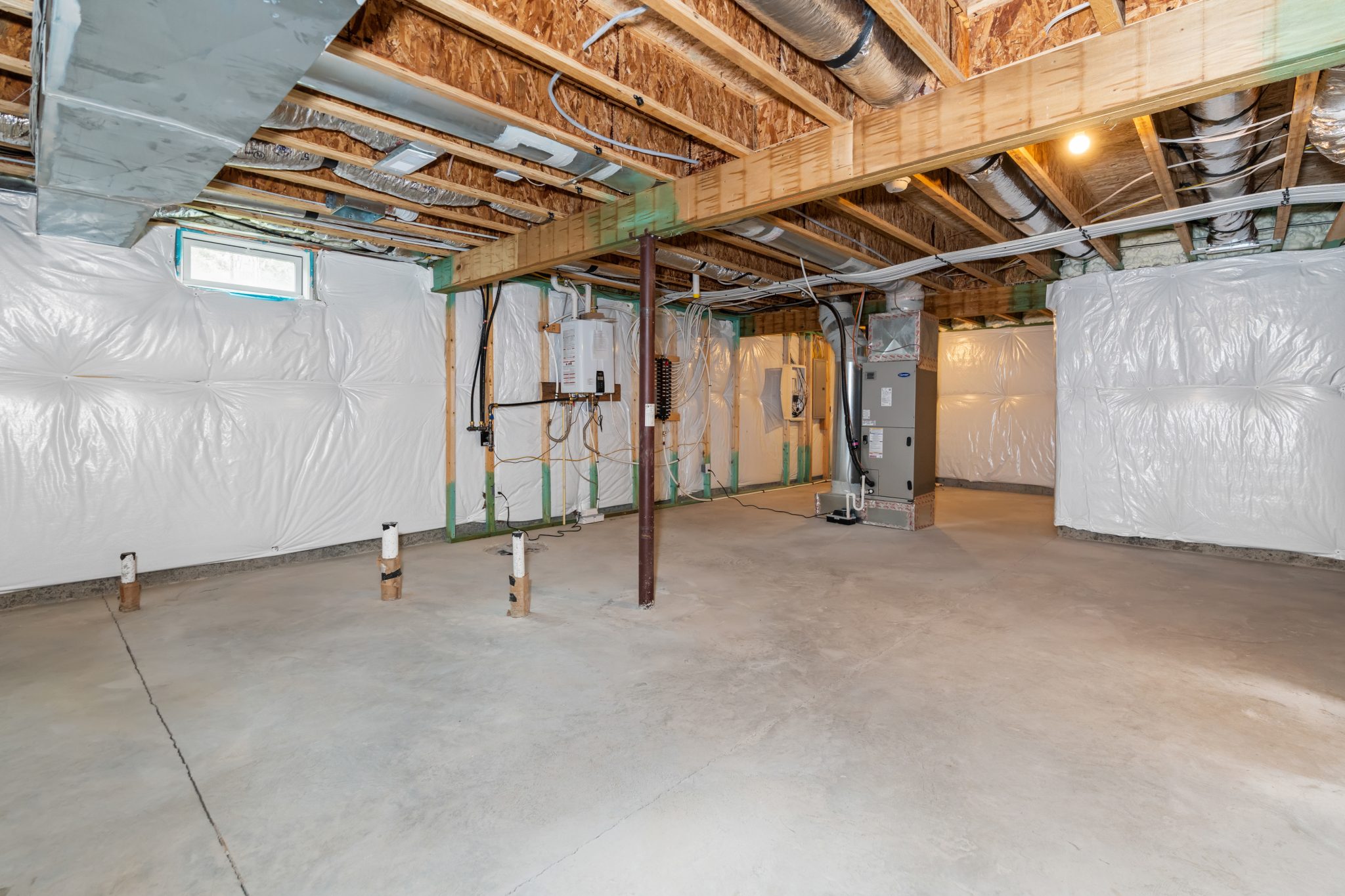 Unfinished basement with a vapor barrier on the walls and exposed ductwork, the starting point when pricing basement finishing cost in Fairfield County