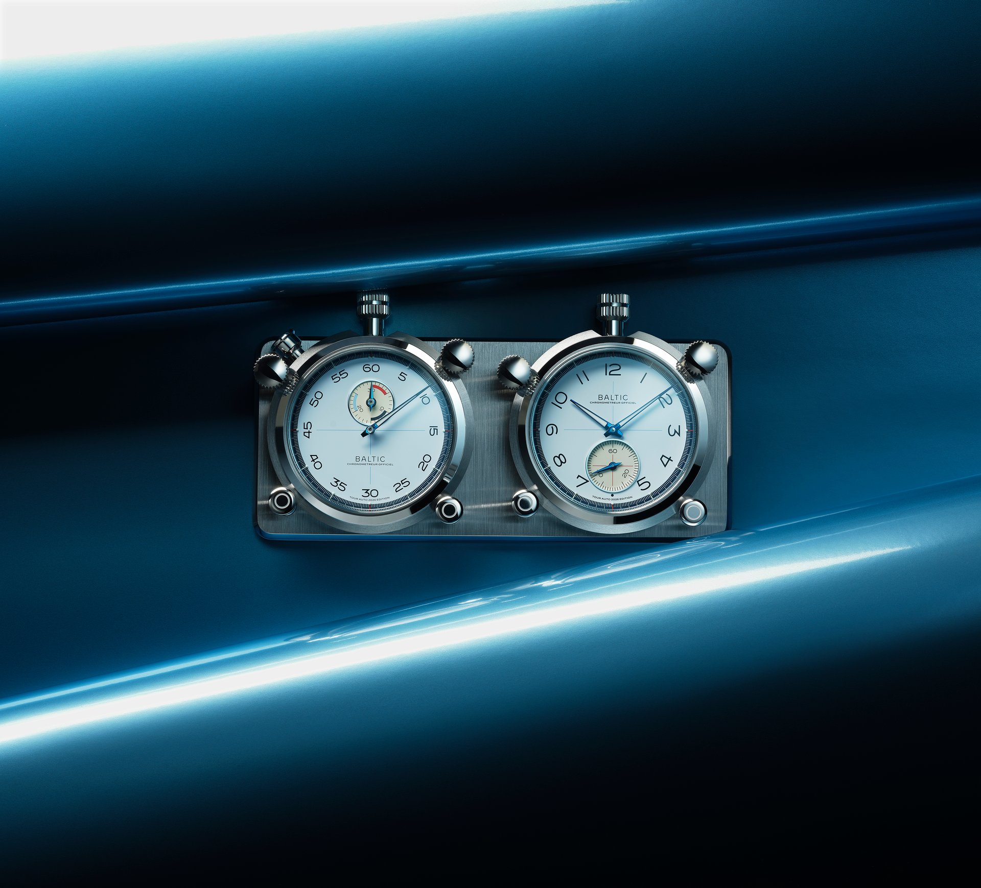 Two Baltic dashboard chronometers on a metal plate, set against a glossy dark blue car interior with light streaks.